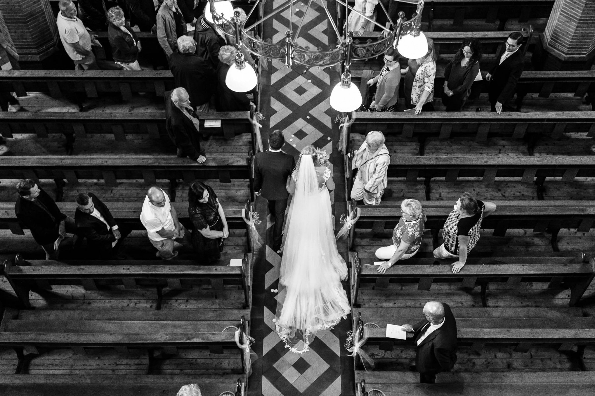 A bride and groom walk down the aisle in a church.