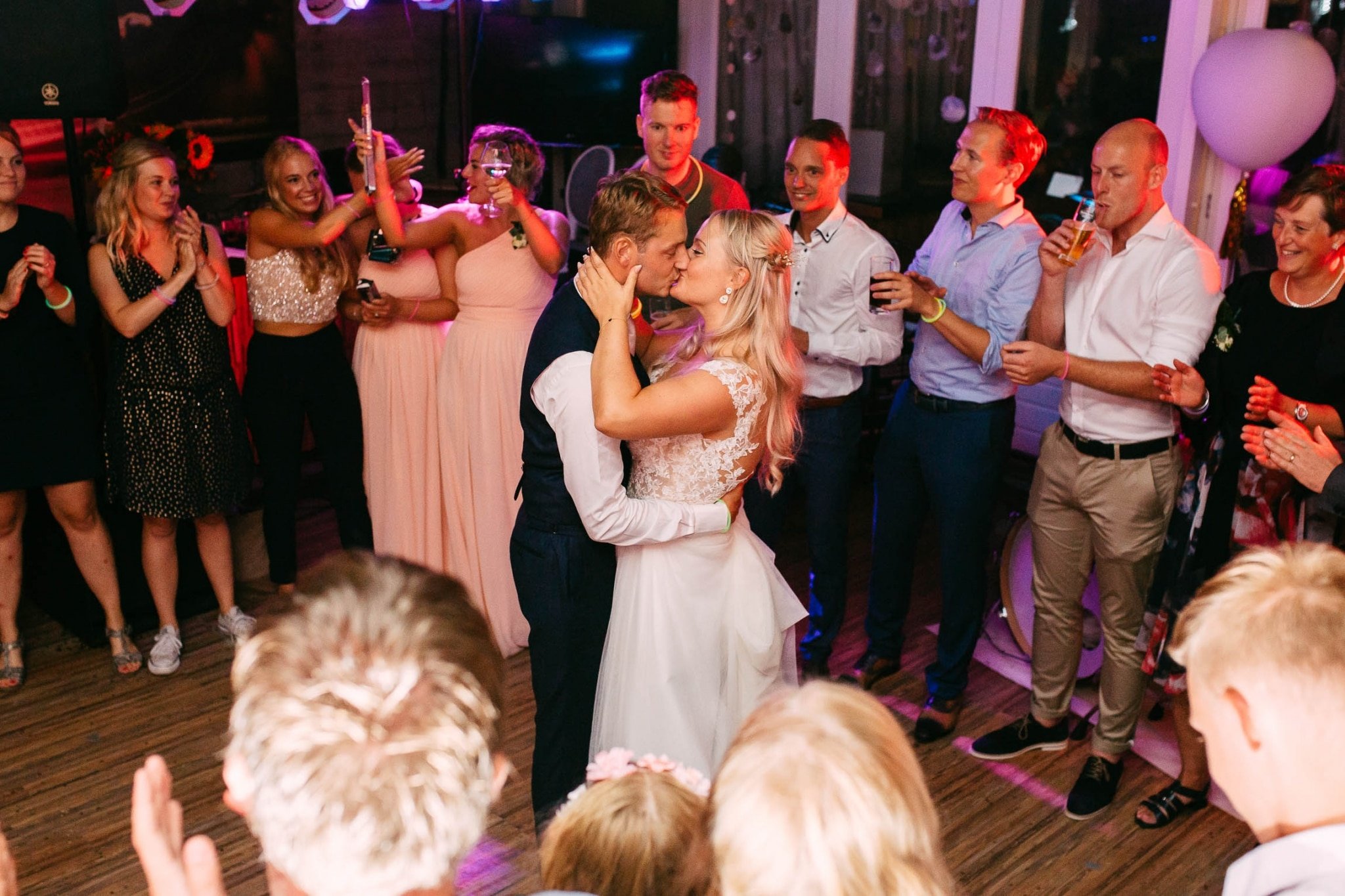 A bride and groom kiss on the dance floor during their wedding reception.