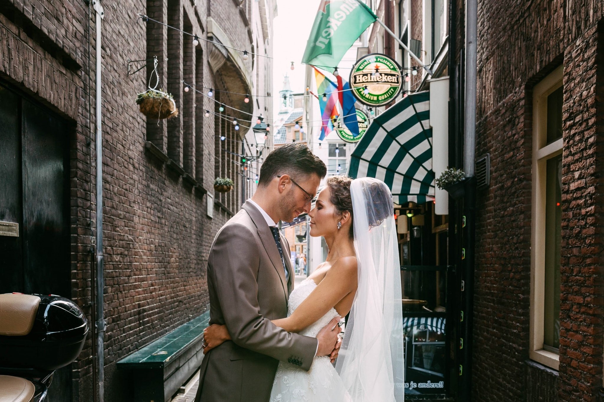 A bride and groom embrace in a narrow alley.