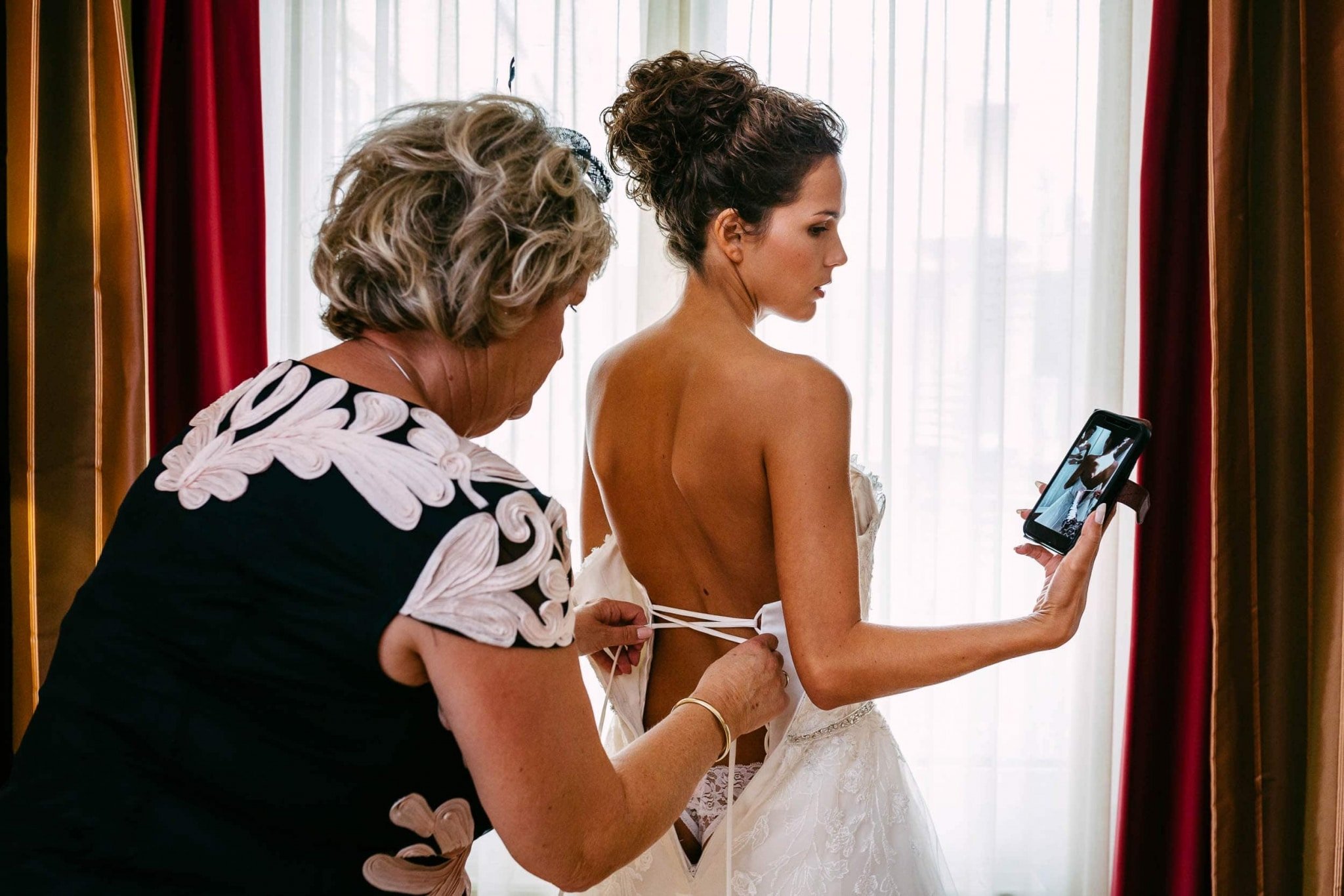 A woman puts on a wedding dress in front of a mirror.