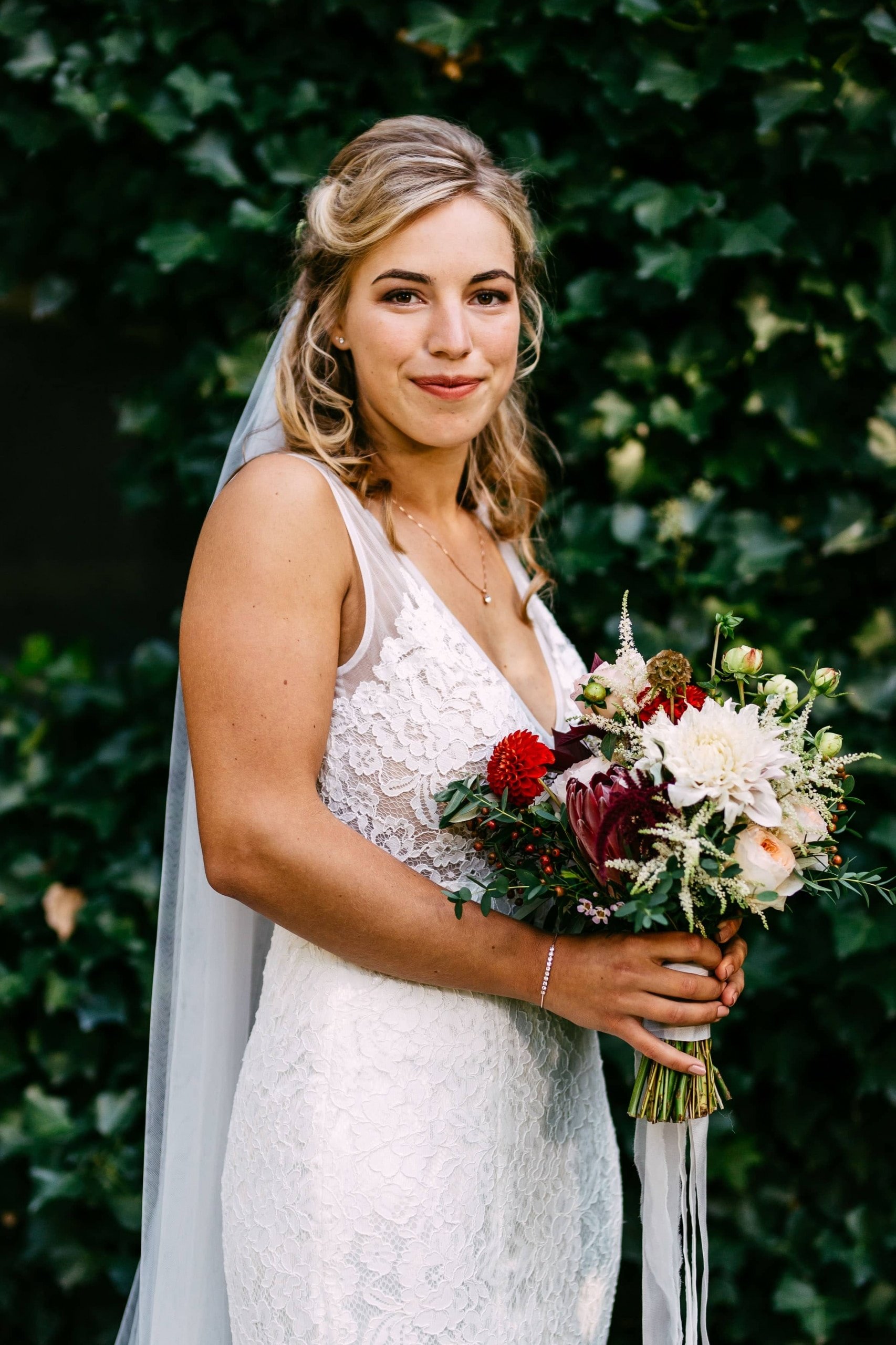 A bride in a lace wedding dress with a bouquet.