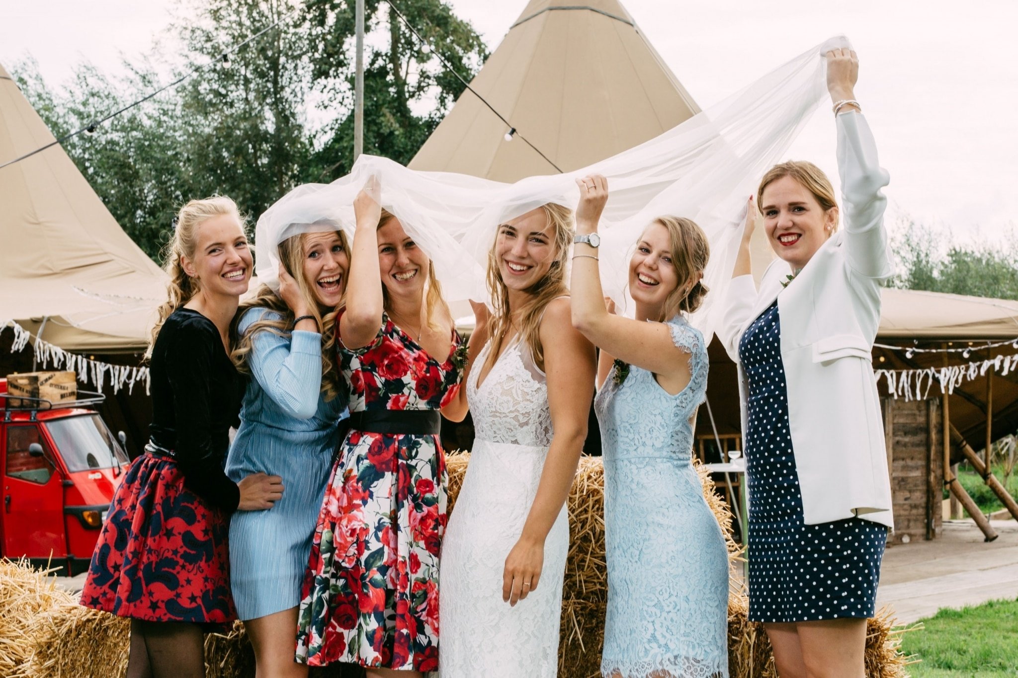 A group of bridesmaids pose in front of a tepee.