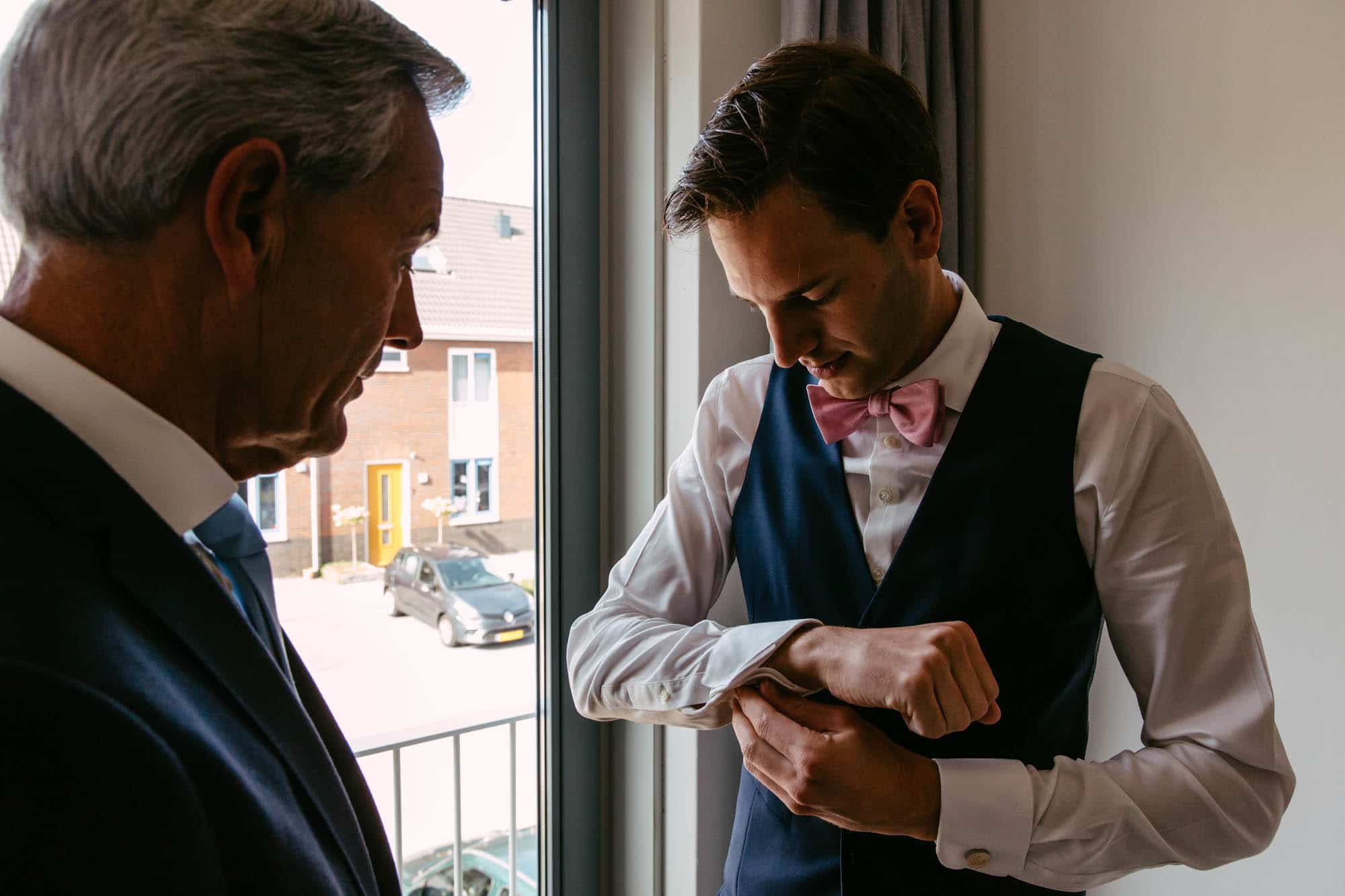 A man in a suit adjusts his watch.