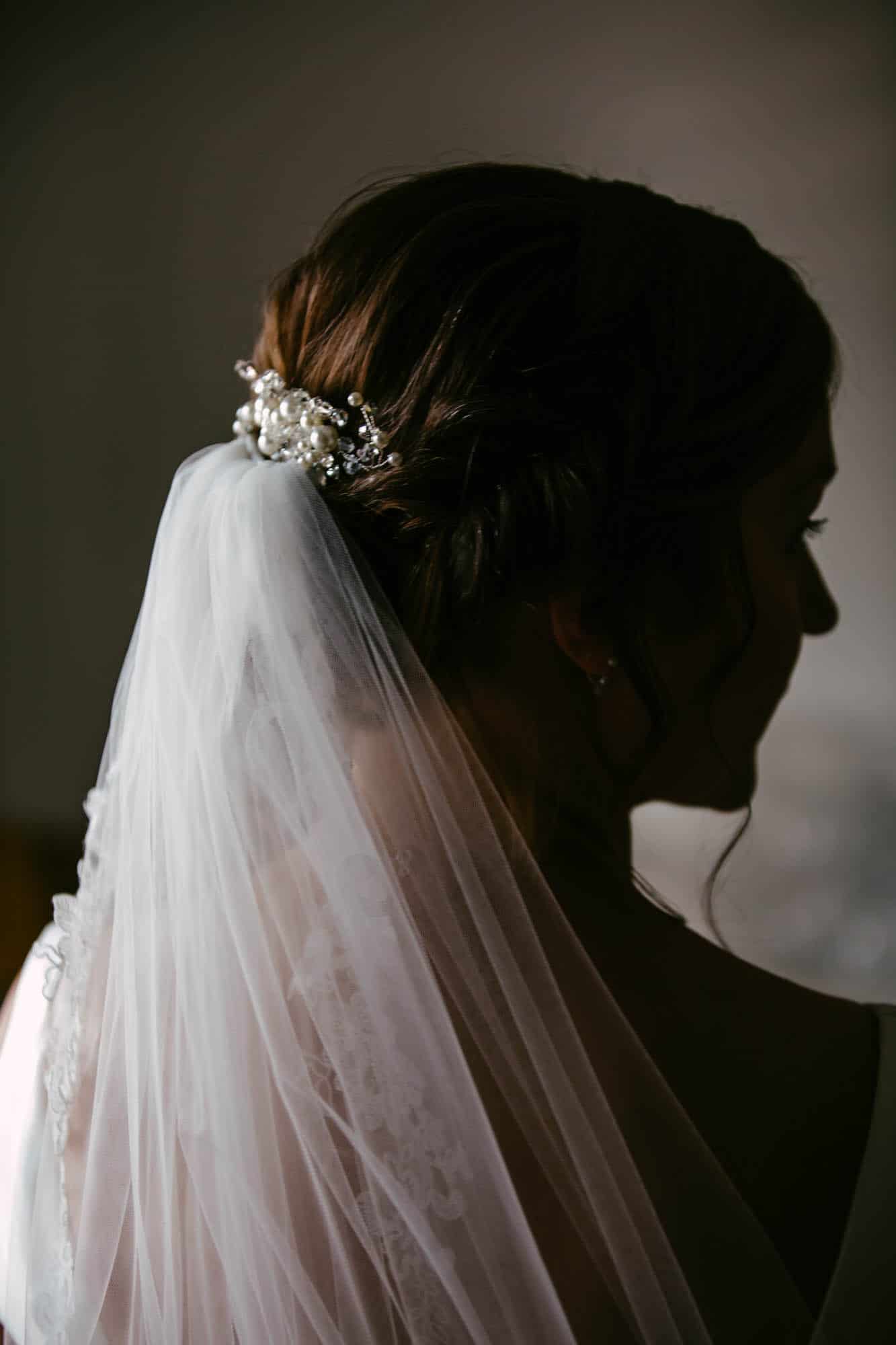 Een bruid met een sluier en parels in het haar.