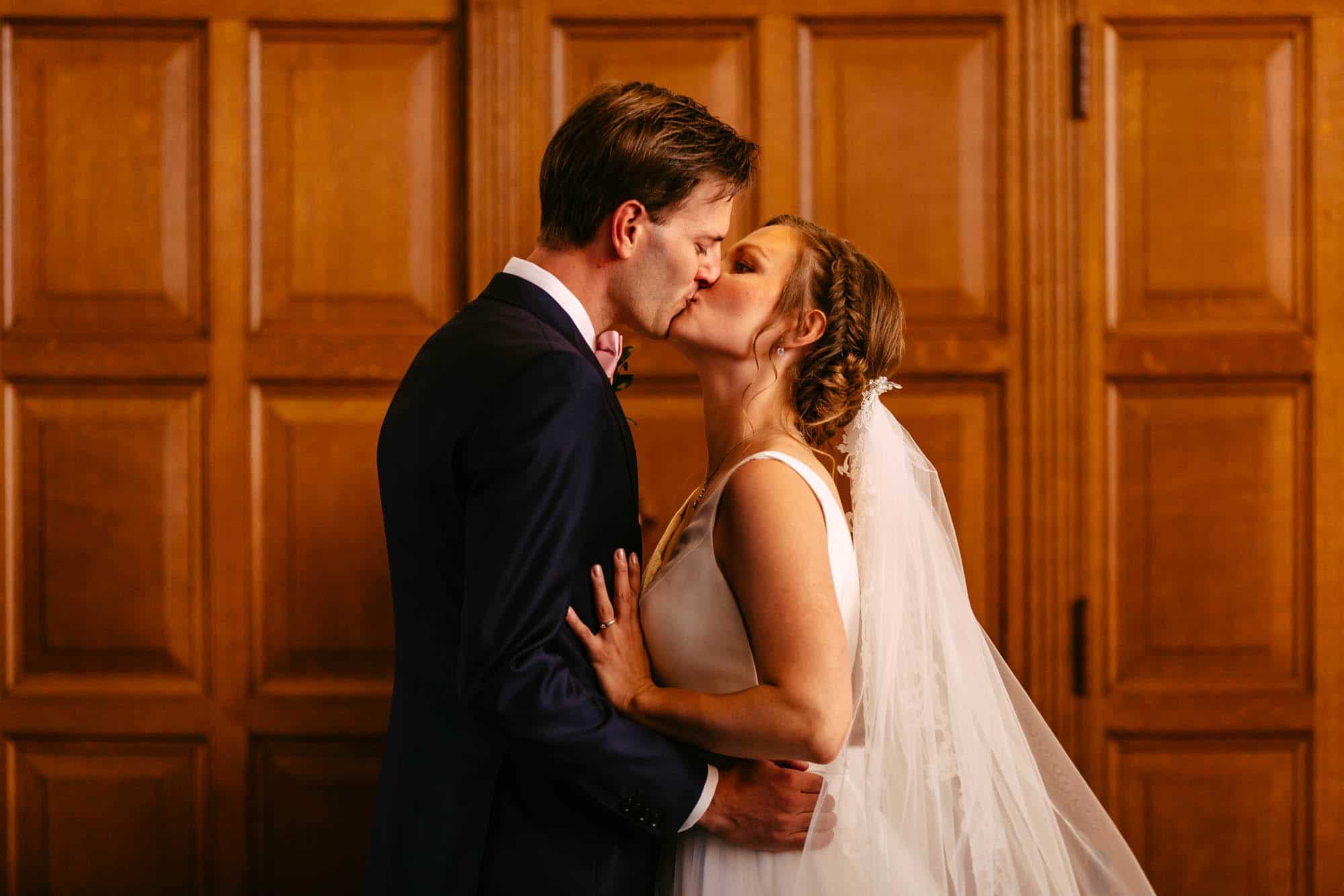 A bride and groom kiss in front of wooden doors.