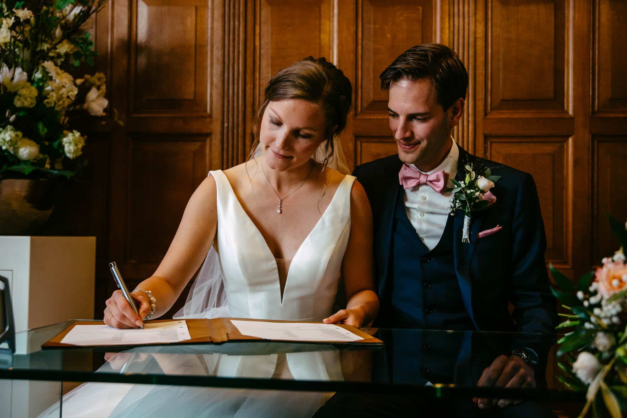 A bride and groom signing their wedding vows at a table.