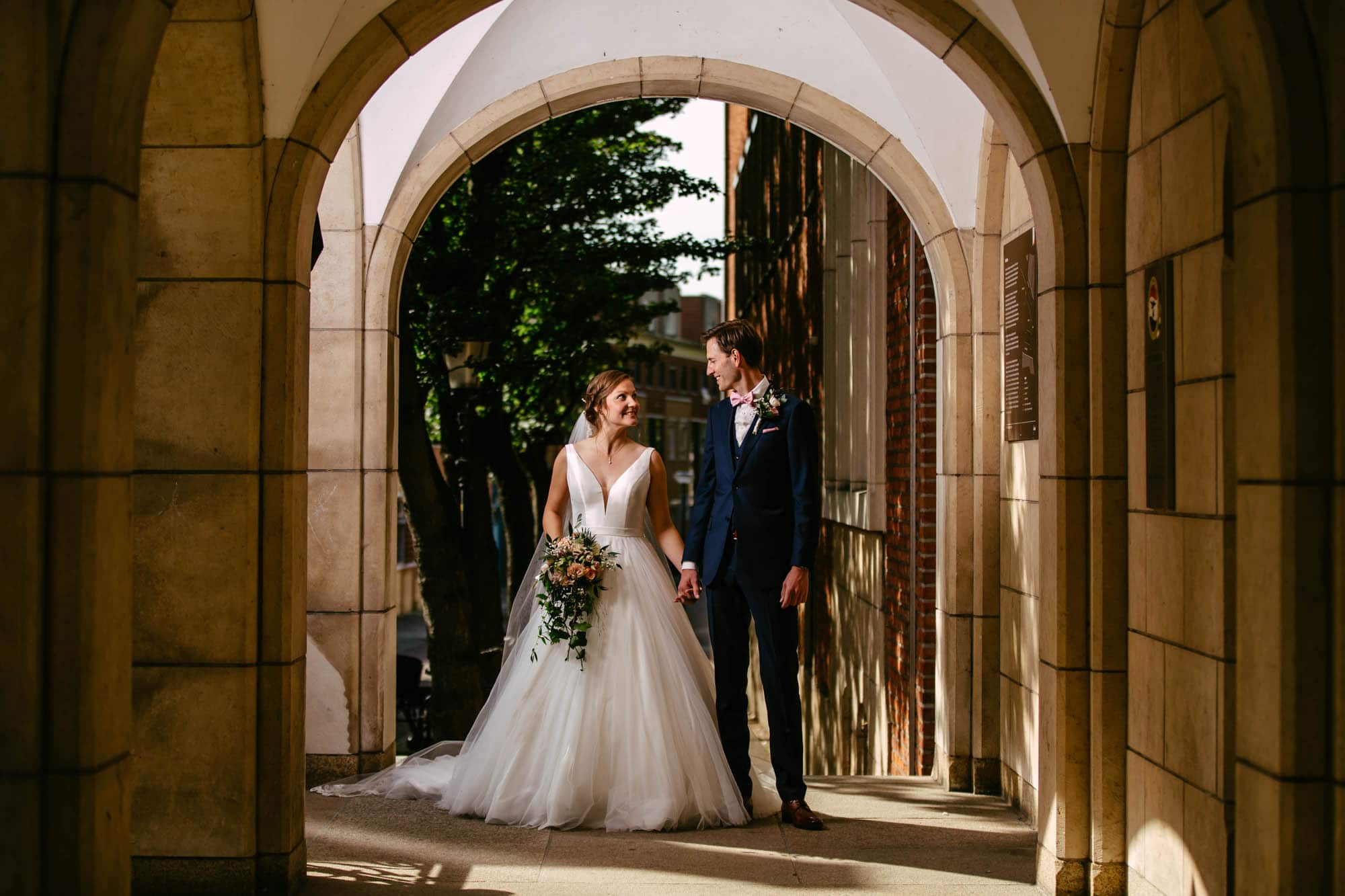 A bride and groom stand in an archway.