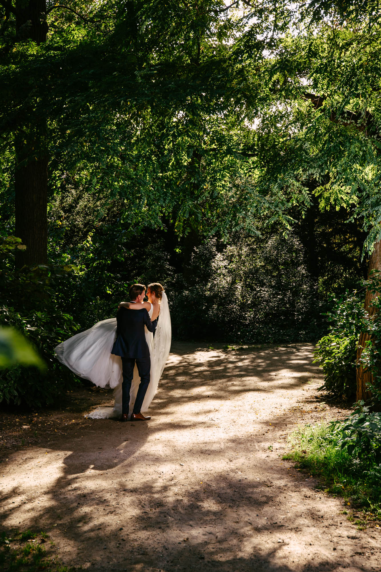 A relaxed bride and groom hugging each other in the forest during their wedding ceremony.