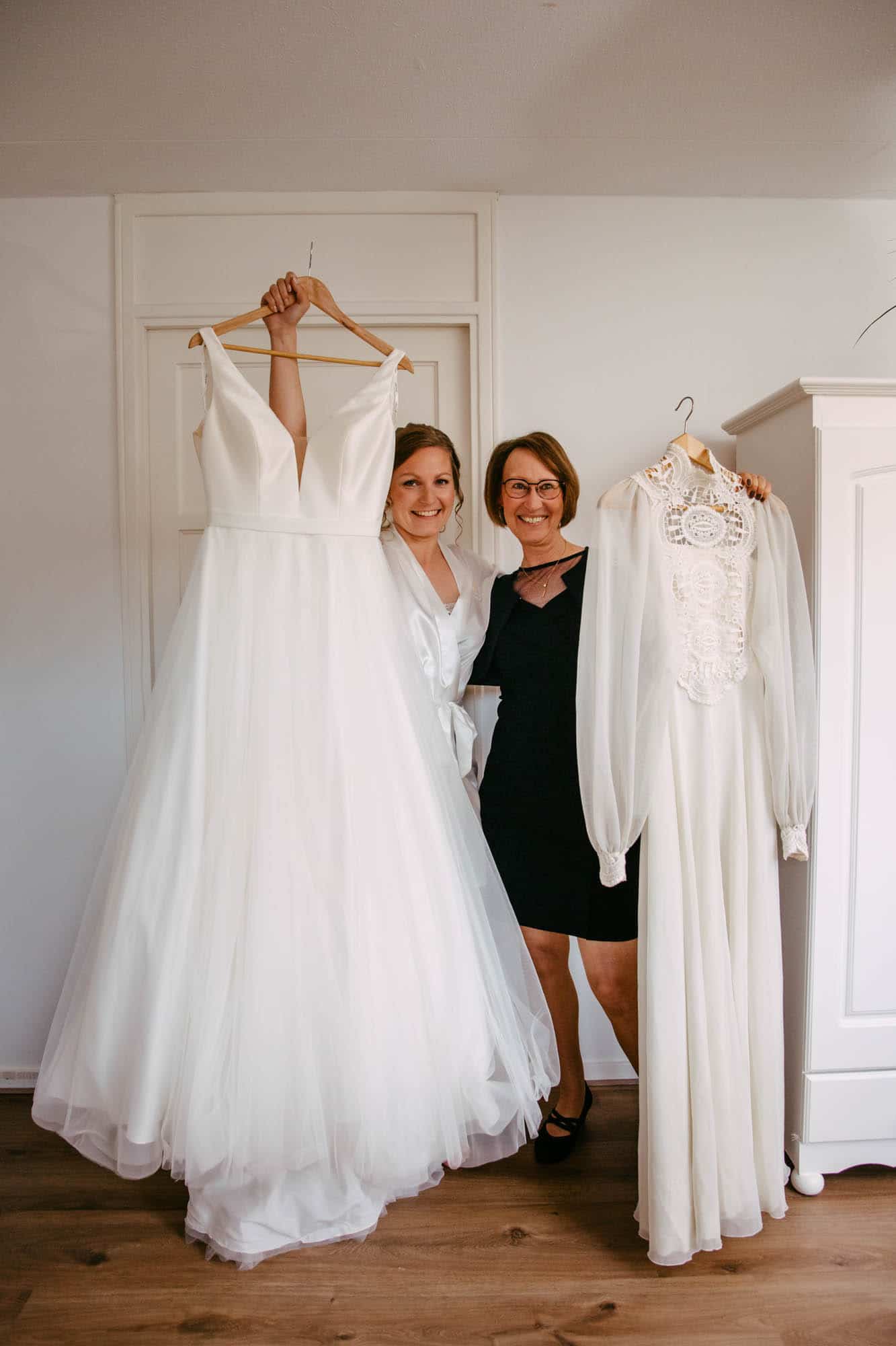 Two brides pose with their wedding dresses.