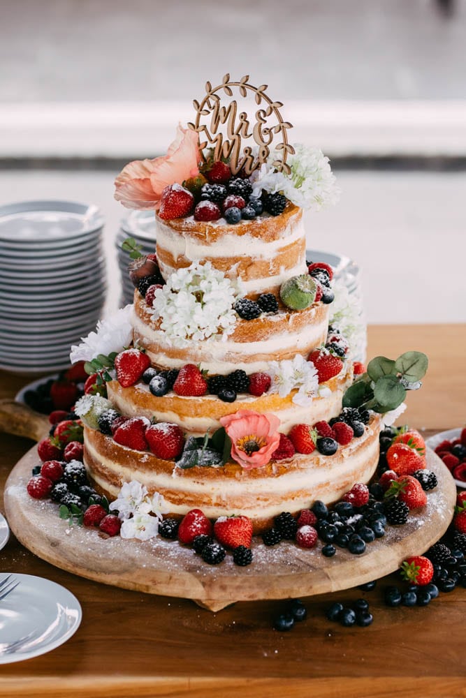 Description: A wedding cake decorated with berries and flowers on top.