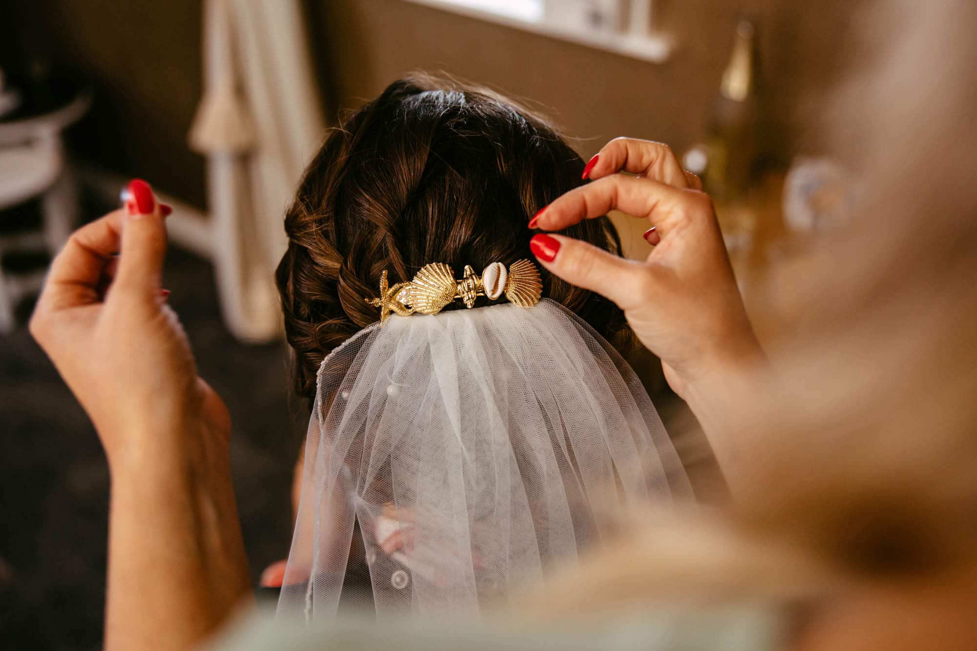 A bride putting on her veil in front of a mirror.