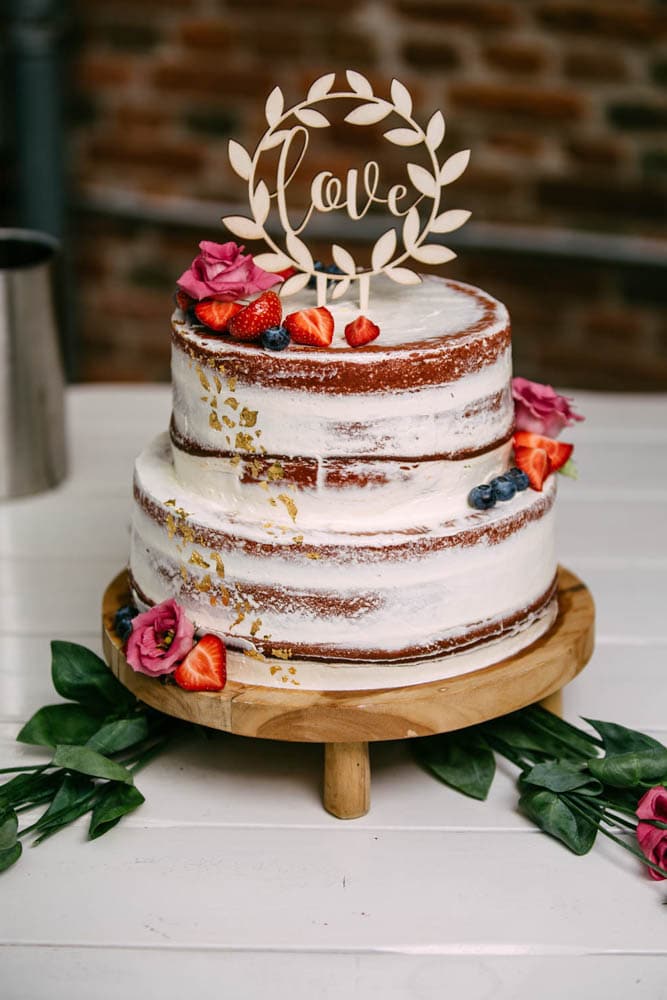 An elegant wedding cake decorated with beautiful flowers and luscious berries, providing exquisite wedding inspiration.