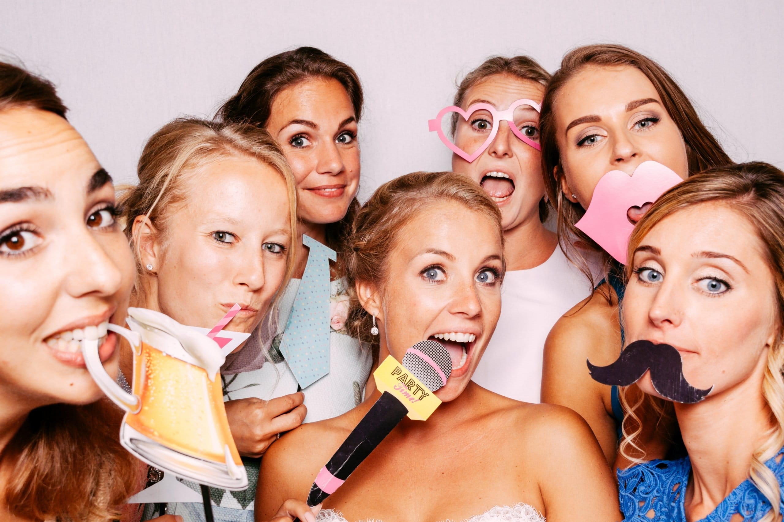 Een groep bruidsmeisjes poseert in een photobooth tijdens een bruiloft.