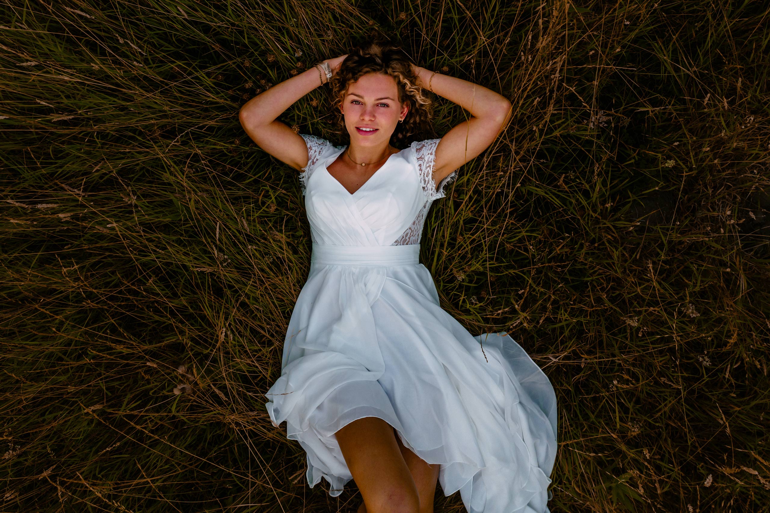 A woman in a white dress relaxing peacefully in the grass.