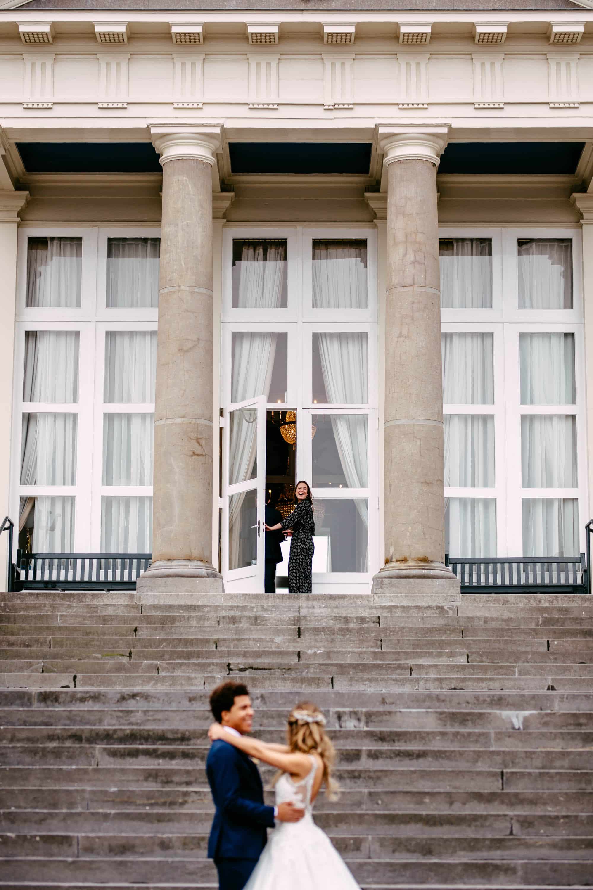 Een bruid en bruidegom staan op de trappen van een gebouw.
