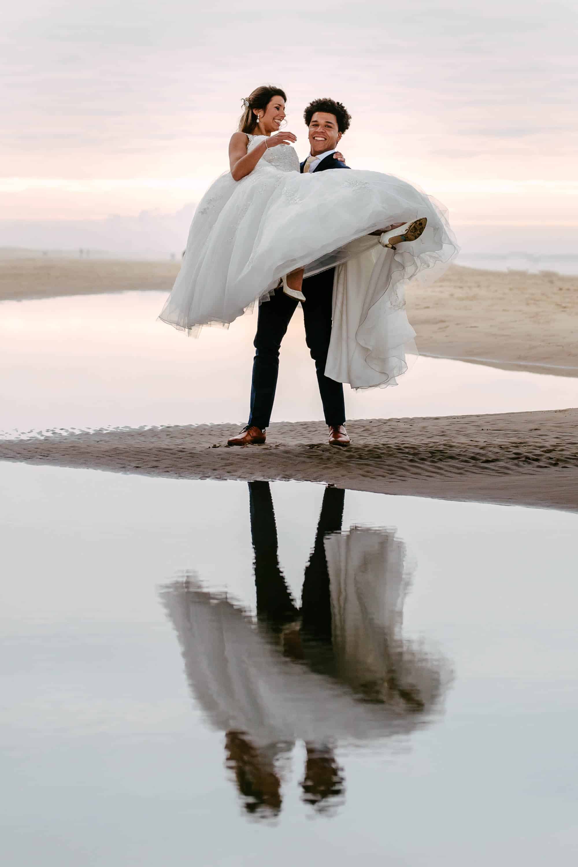 Een bruid en bruidegom poseren voor een foto op het strand.