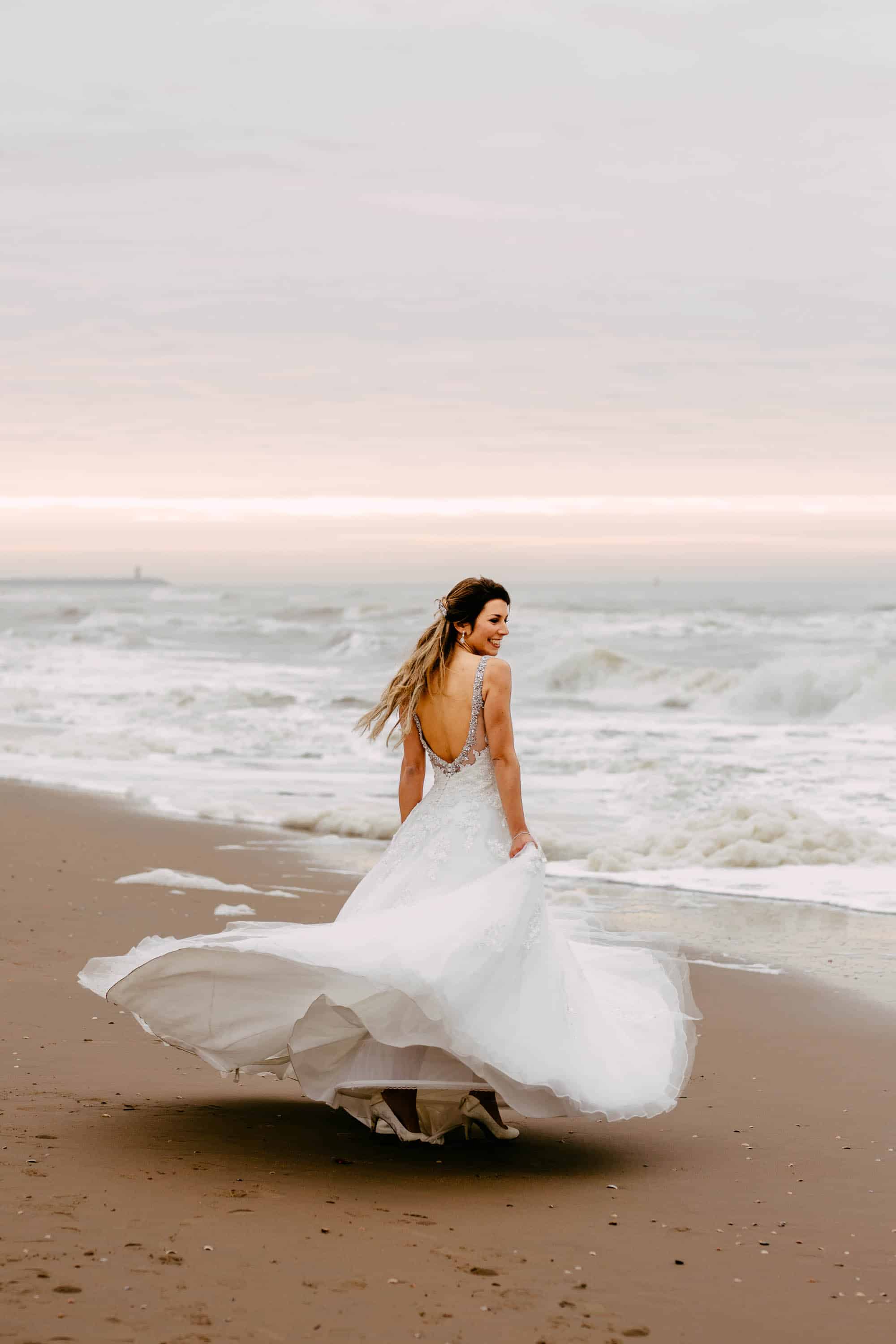 Een bruid die in haar trouwjurk over het strand rent.