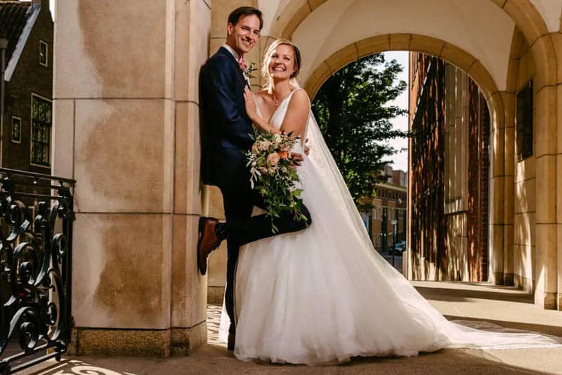 A bride and groom pose in front of an archway. View sample weddings.