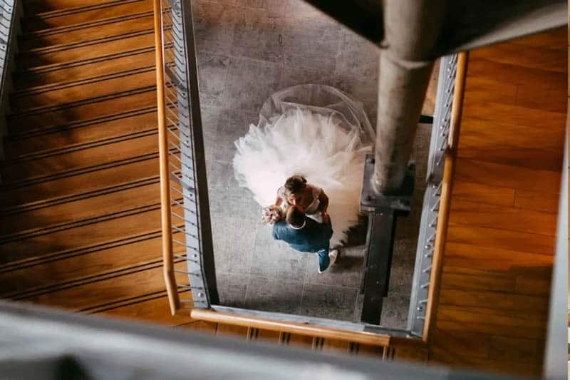 A couple celebrate their wedding day by posing on the steps of a building.
