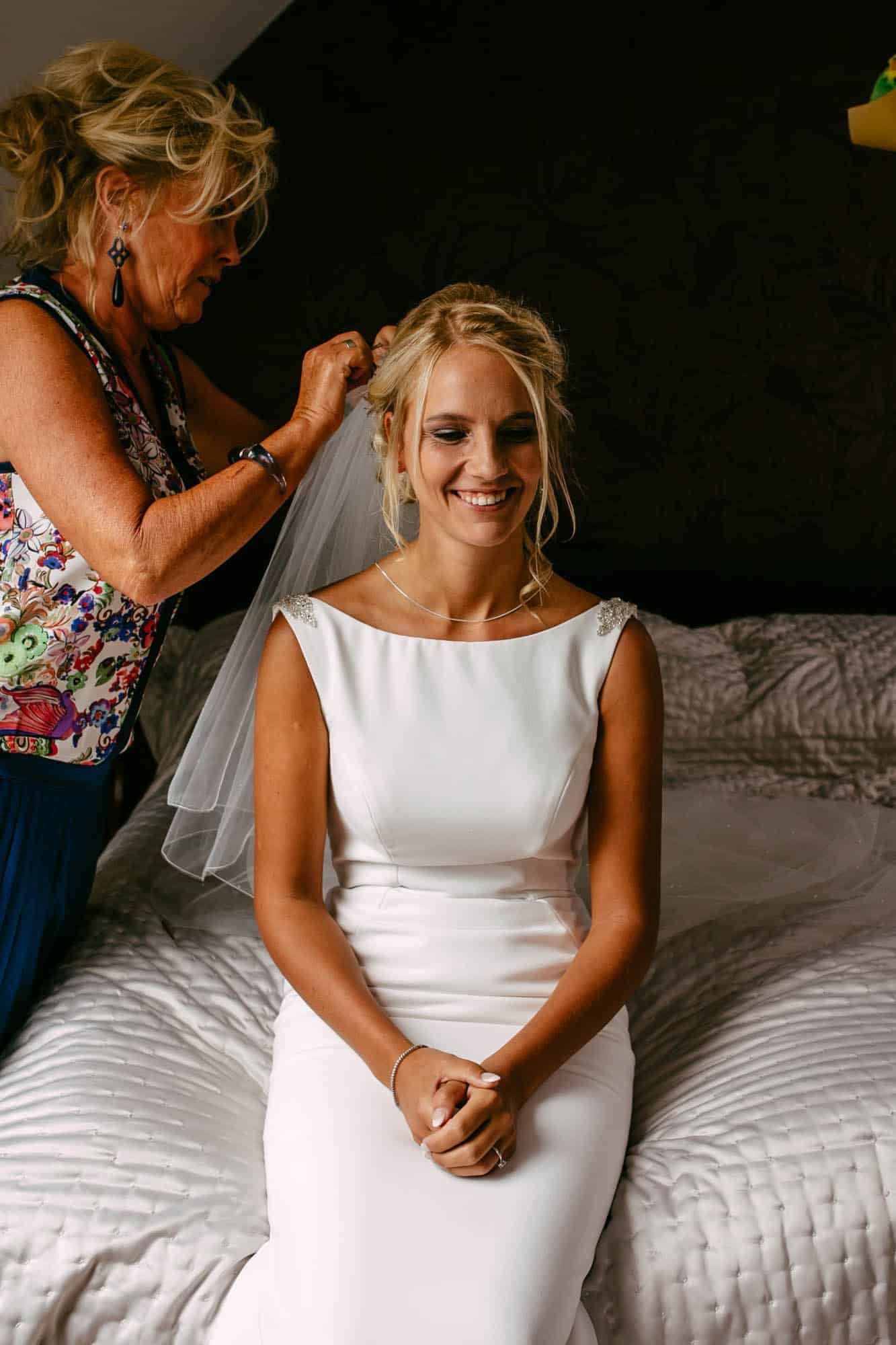 A bride has her hair cut by a woman in a white dress.