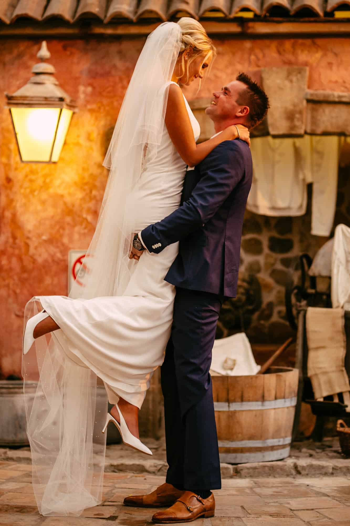 A bride and groom hug in front of a wine cellar.