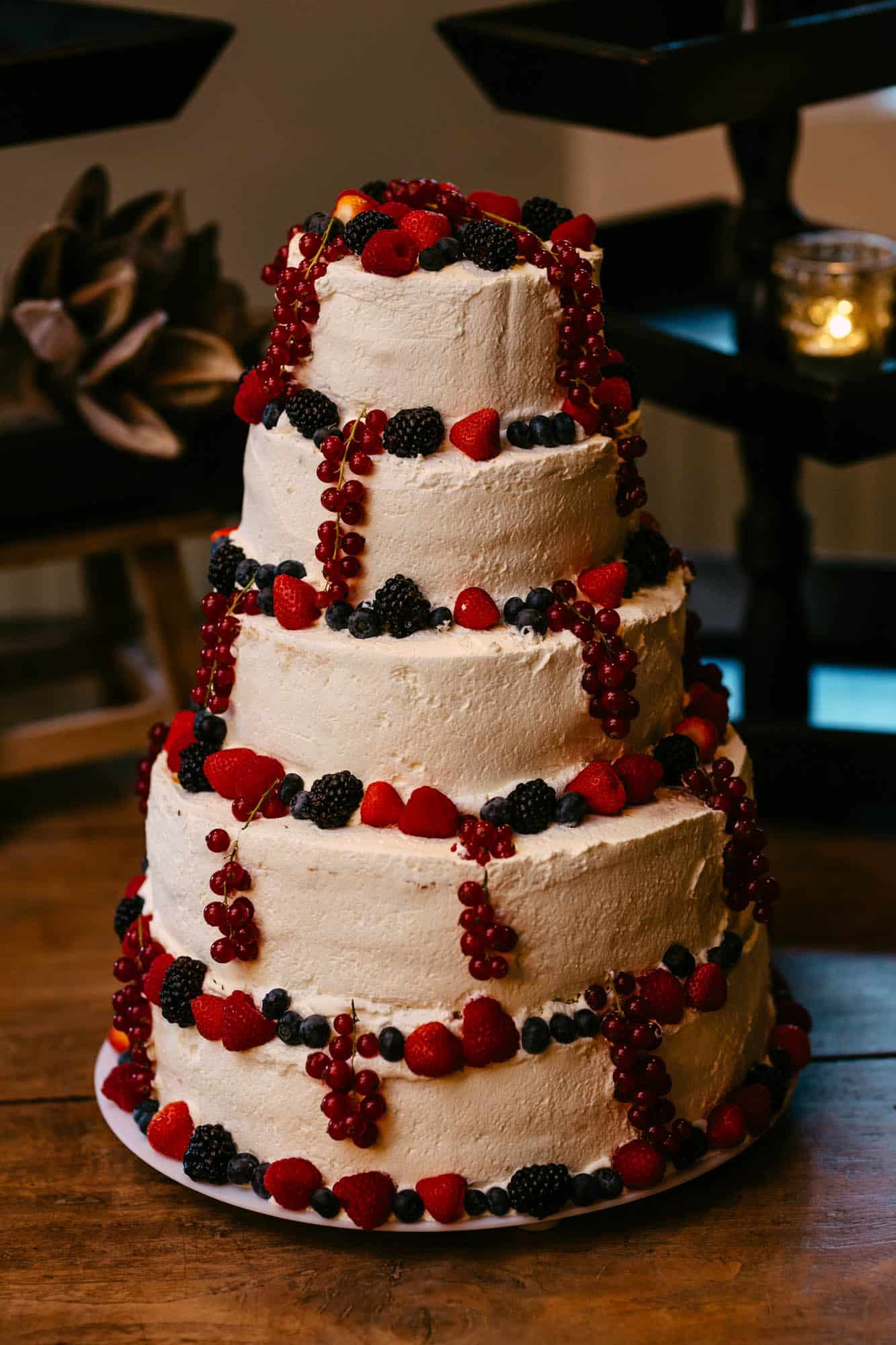 A wedding cake with three layers and berries on top.