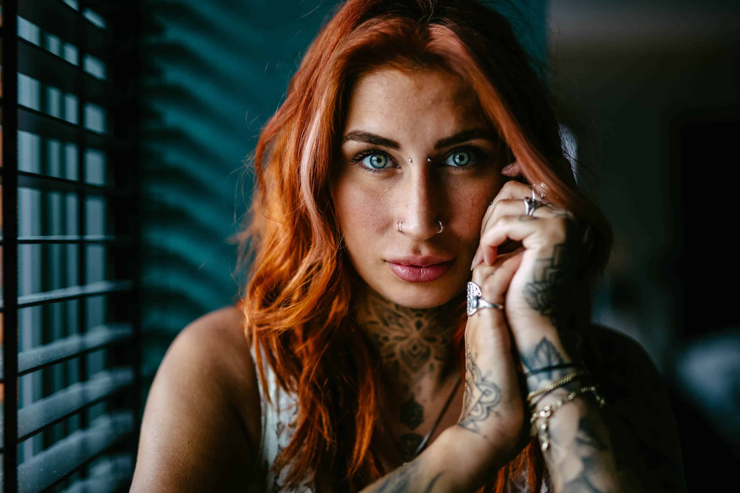 A woman with red hair and tattoos poses sensually during a boudoir shoot in Hoek van Holland.