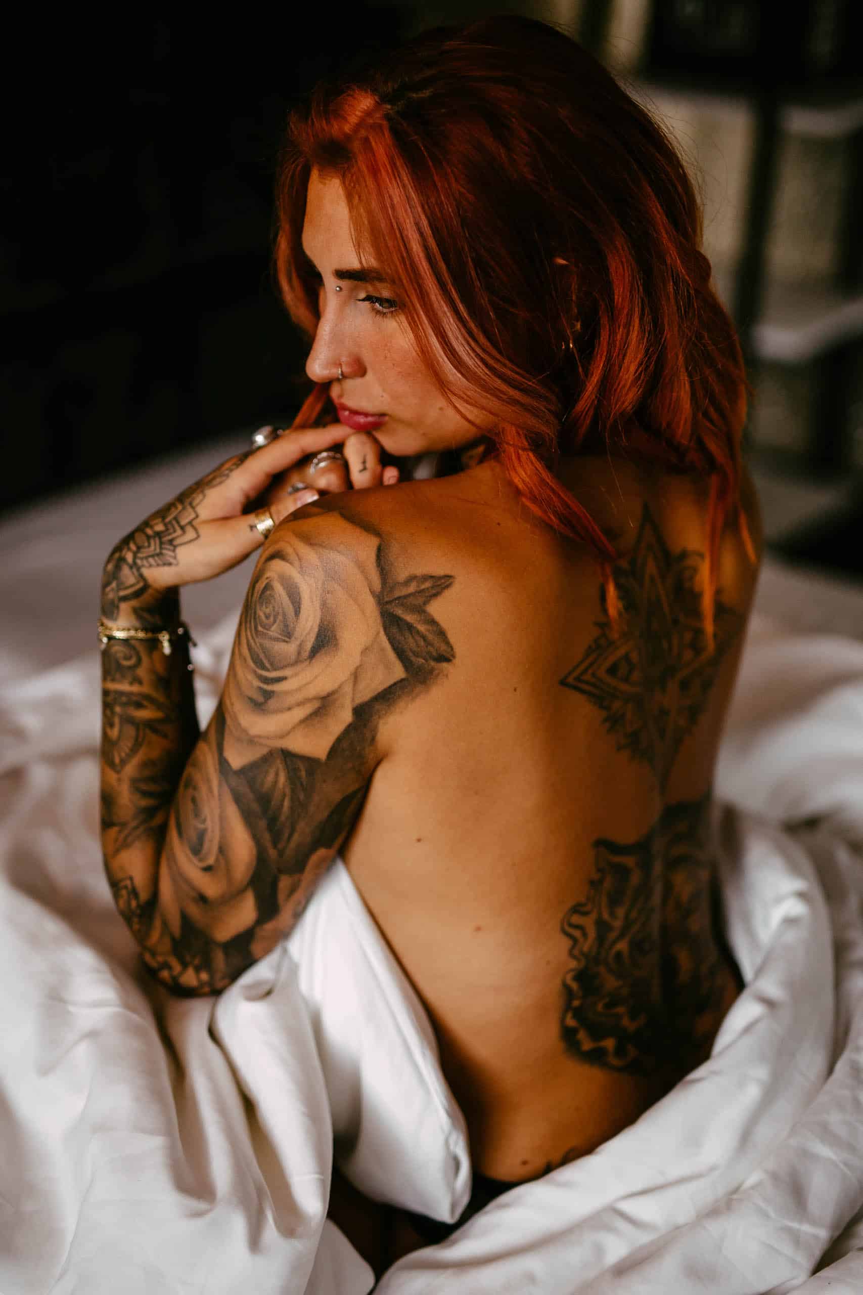 A woman with red hair sitting on a bed during a boudoir shoot in Hoek van Holland.