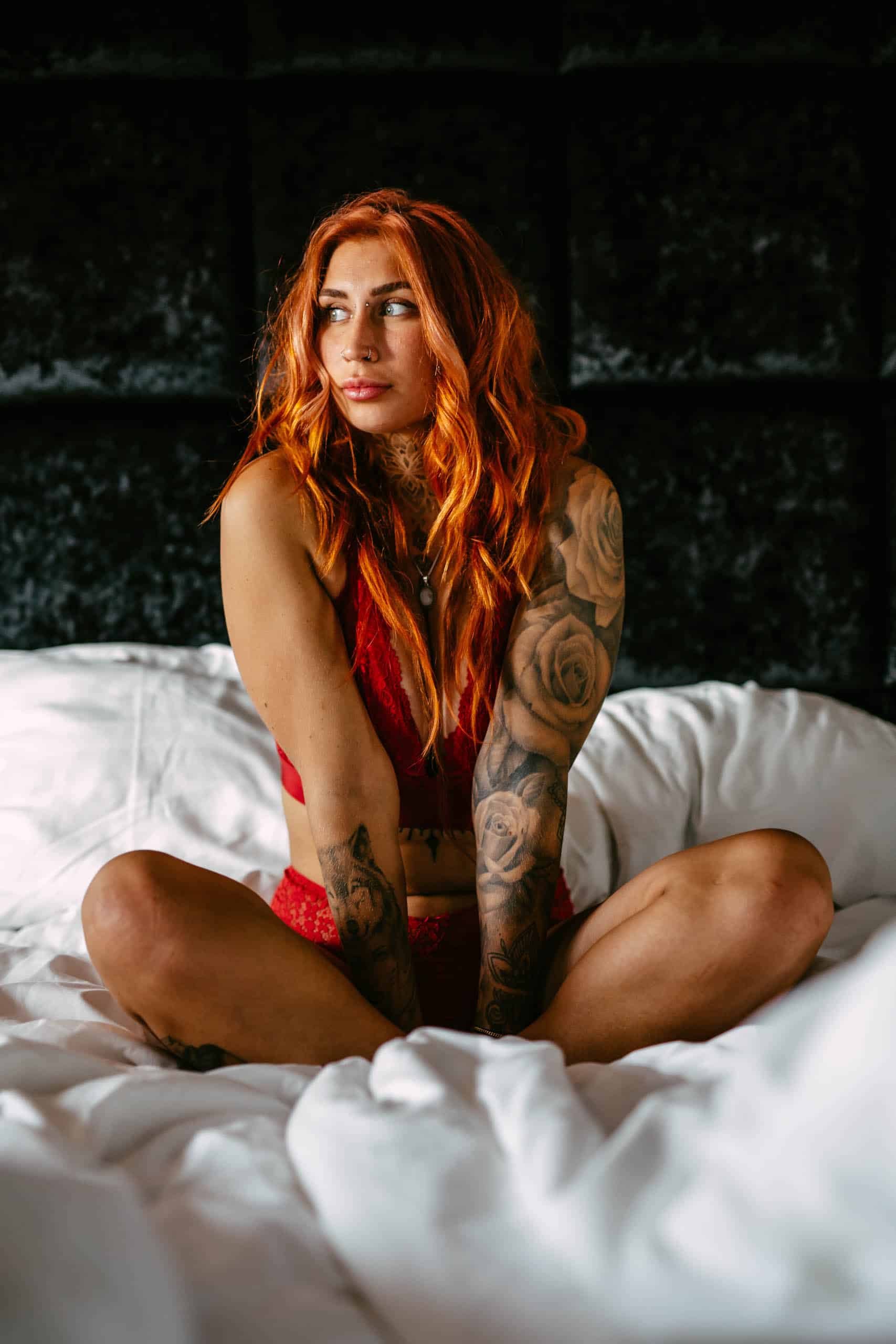 A woman with red hair sitting on a bed during a boudoir shoot in Hoek van Holland.