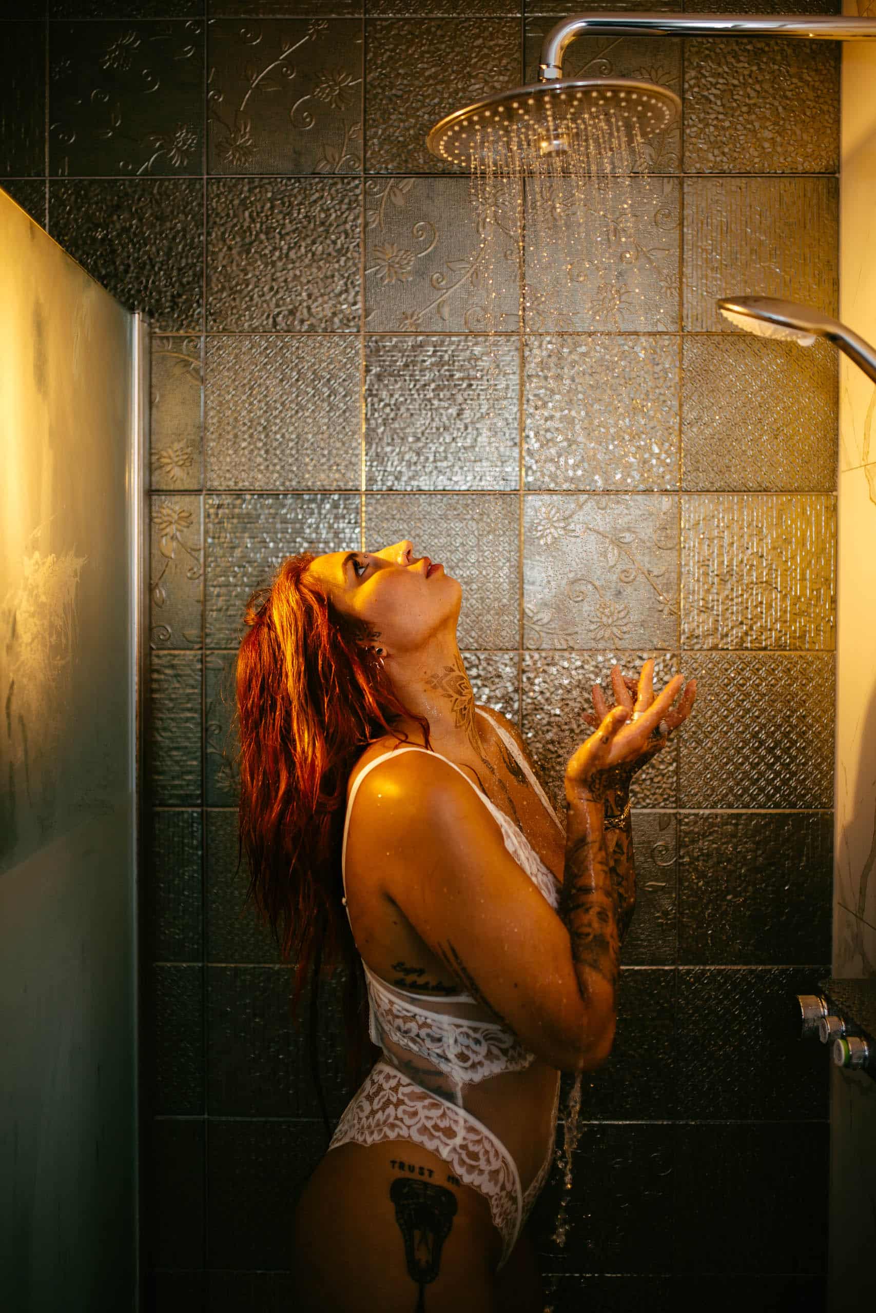 A woman in a boudoir shoot in Hoek van Holland, standing in a shower while water comes out of her face.