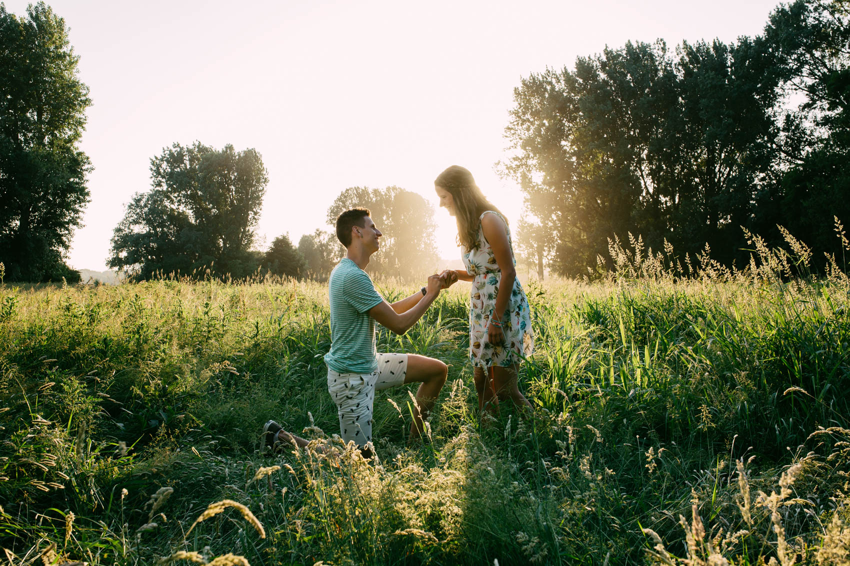 A man and a woman hold a romantic love shoot in a field of tall grass.