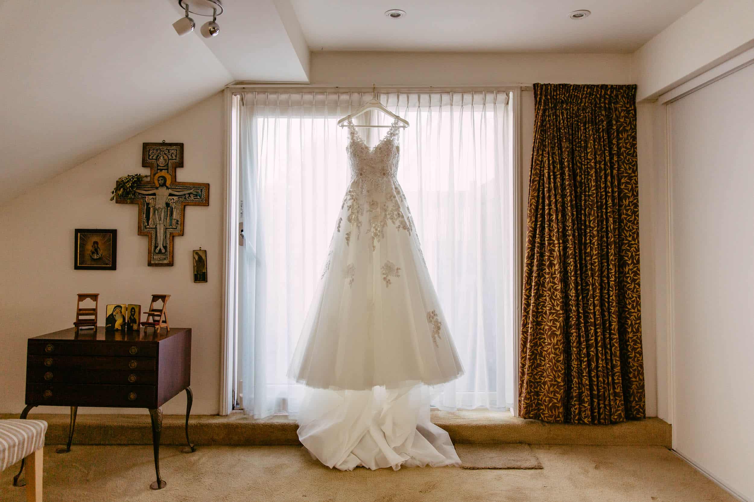 A wedding dress from a botanical garden, hanging in a room with a window in Delft.