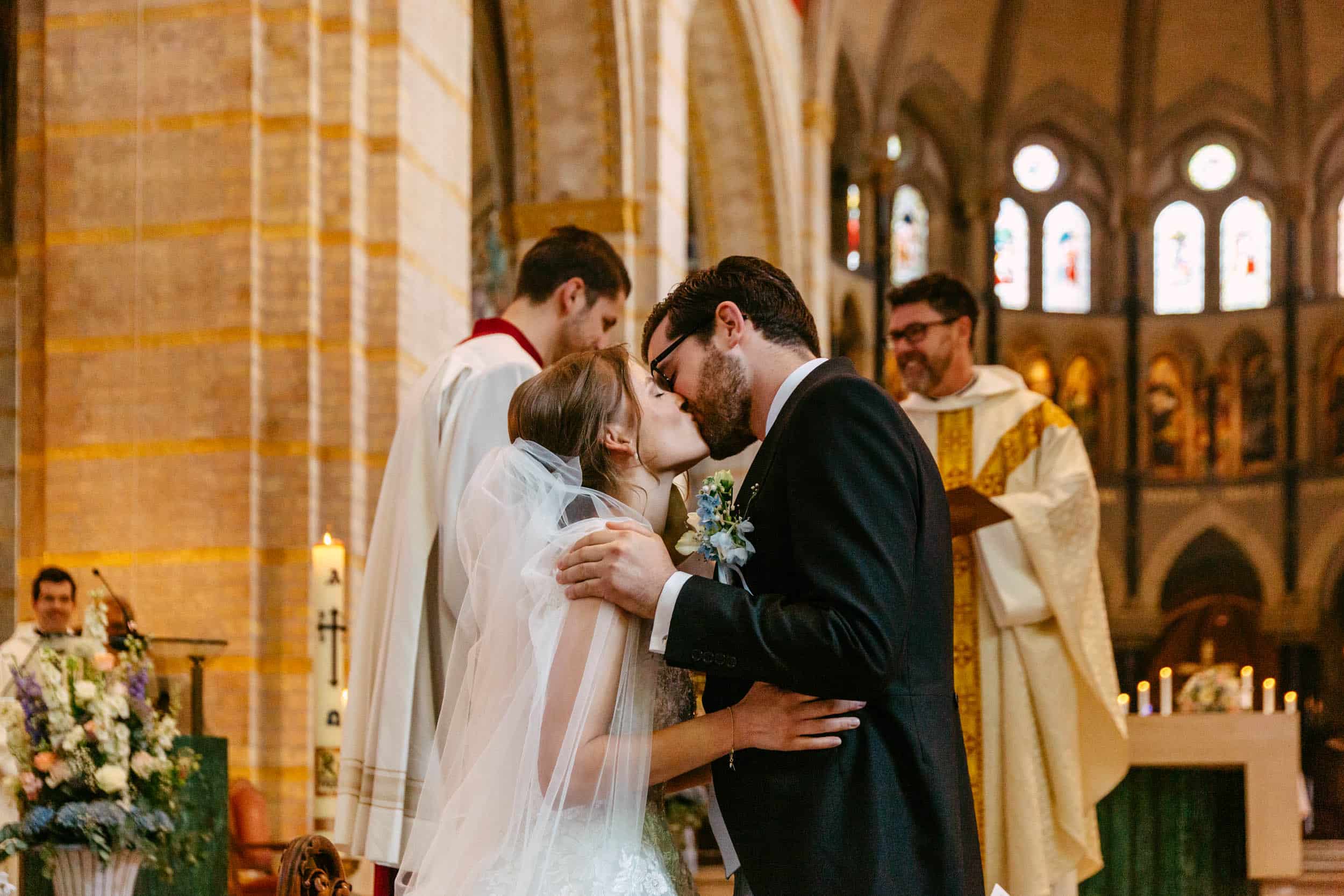 Een bruid en bruidegom kussend bij een Trouwerij in een kerk.