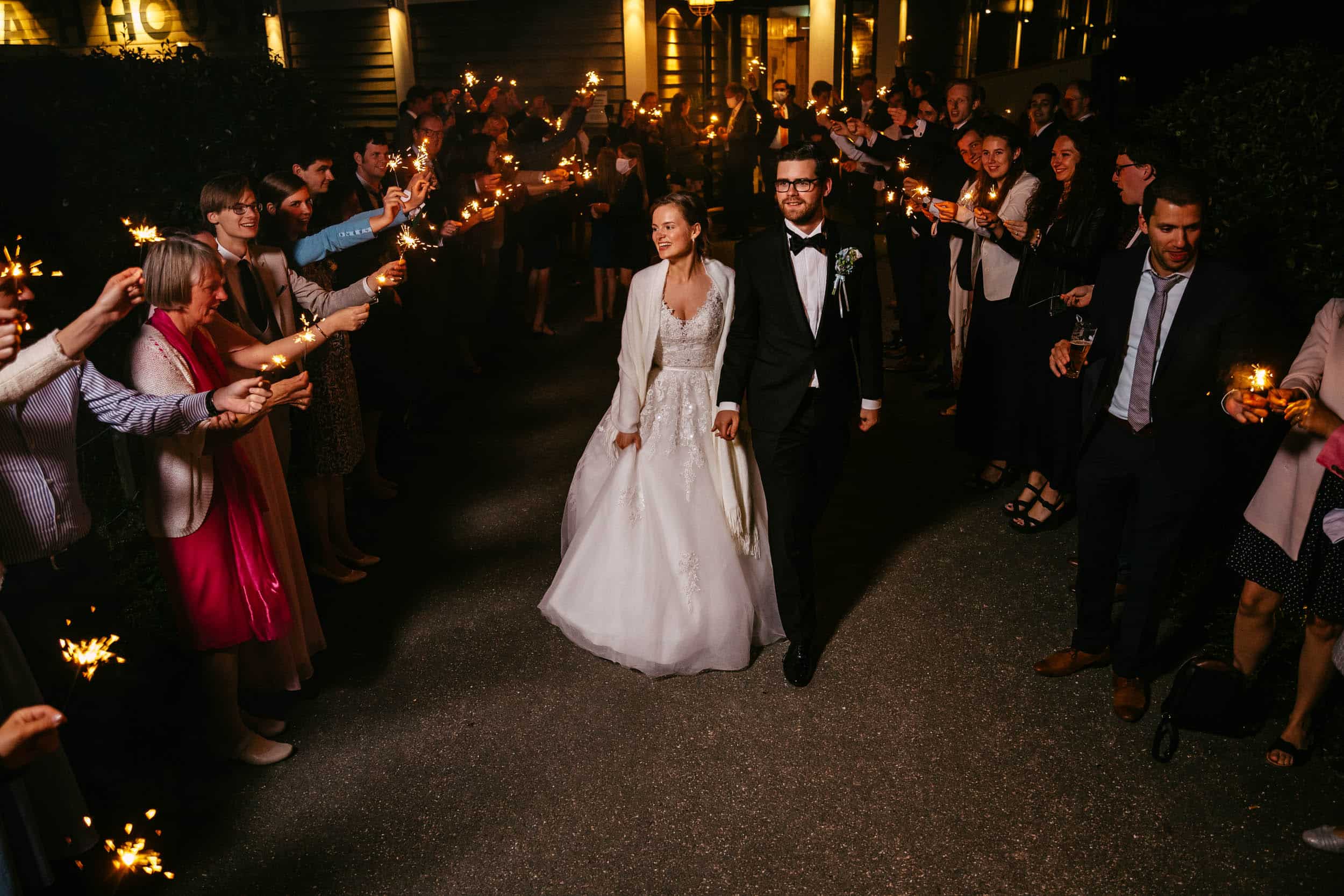 A bride and groom, surrounded by the enchanting atmosphere of a Delft botanical garden, share a magical moment as they walk hand in hand, accompanied by the mesmer