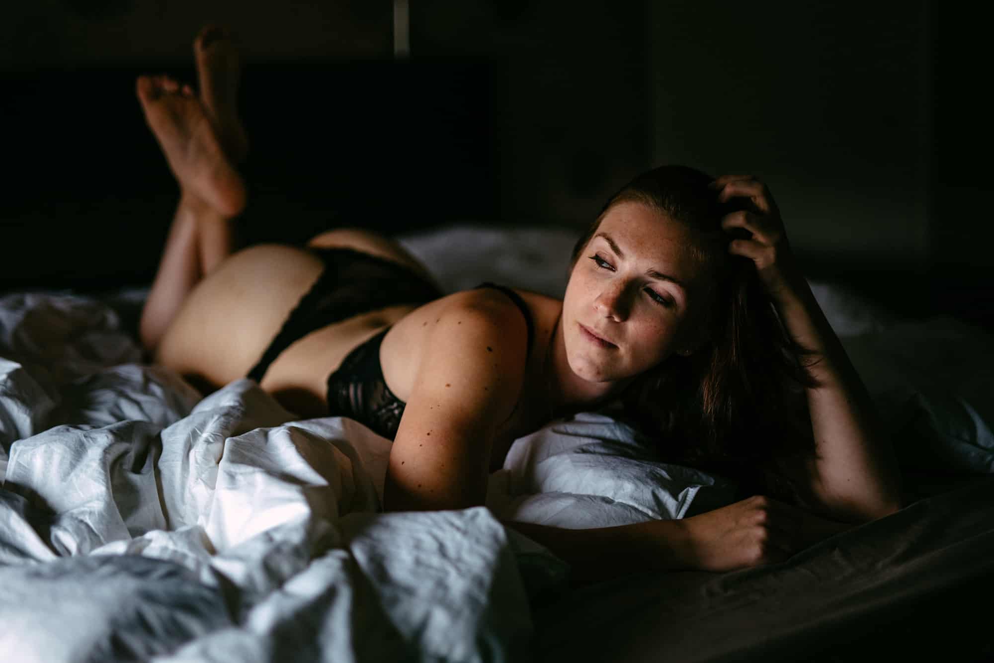 A woman in black lingerie lying on a bed.