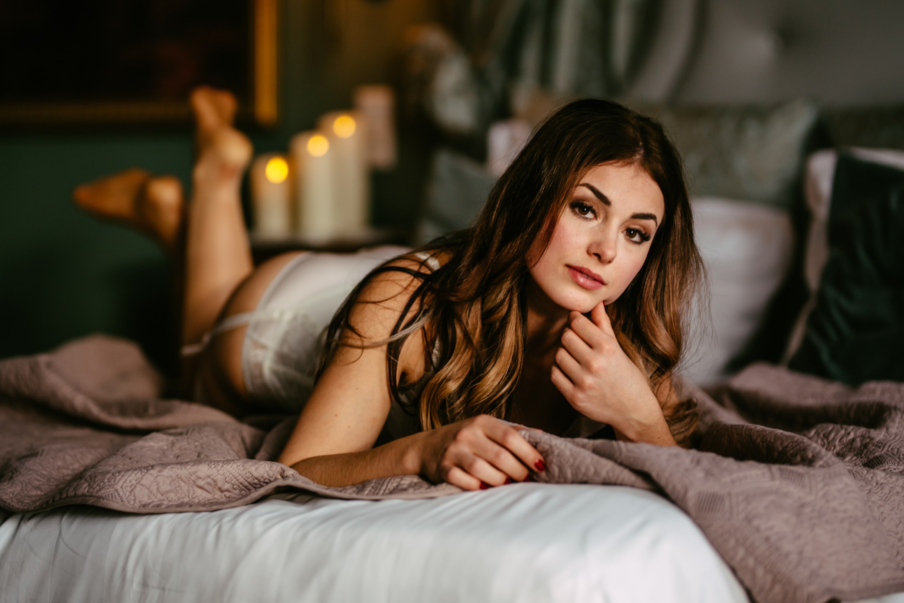 Een mooie vrouw liggend op een bed met kaarsen.
