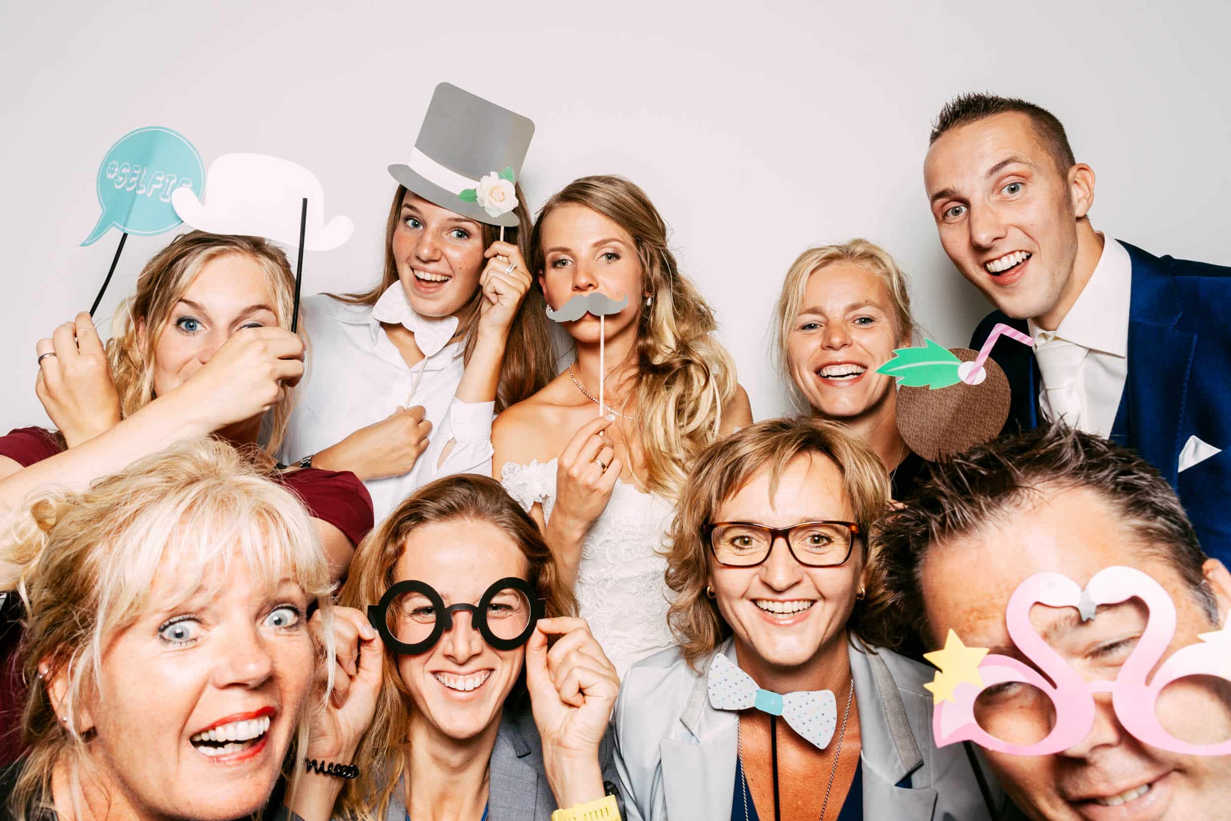 Een groep mensen poseert in een photobooth op een bruiloft.