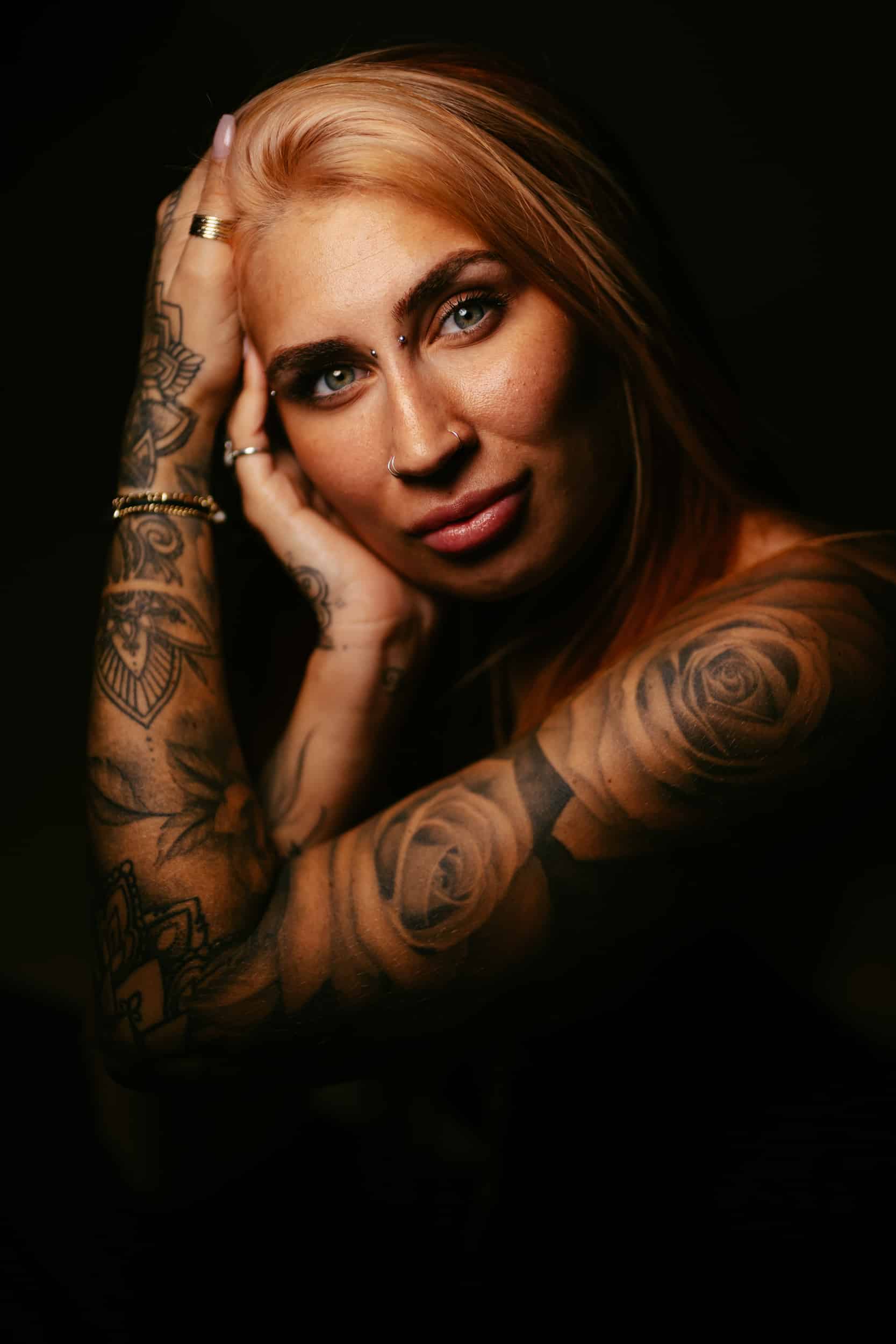 A professional portrait photographer capturing a woman with tattoos during a beautiful photo session.