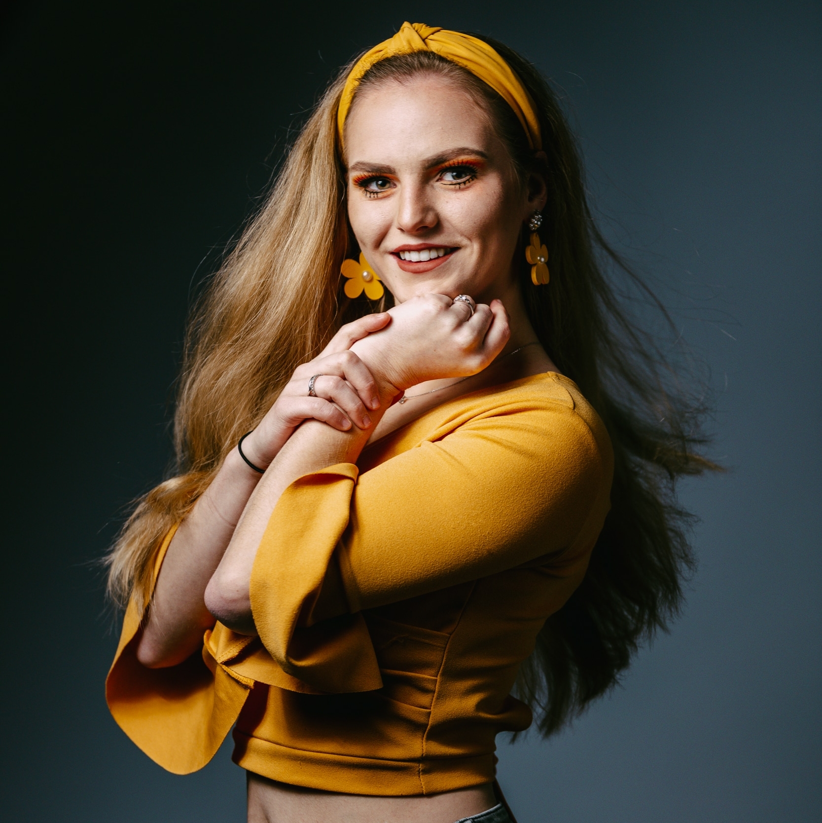 A young professional portrait photographer capturing a woman in a vibrant yellow top for a photo shoot.