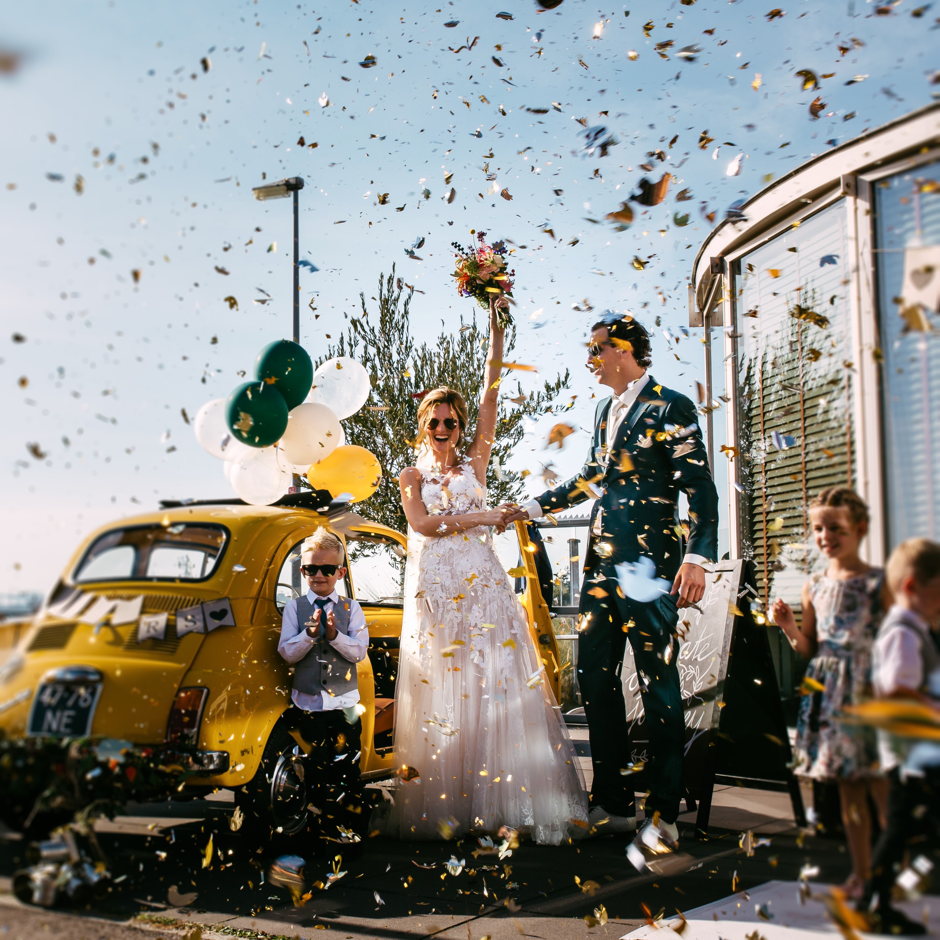 Een bruid en bruidegom worden op hun bruiloft omringd door confetti bij de mijn torpedoloods in hoek van holland