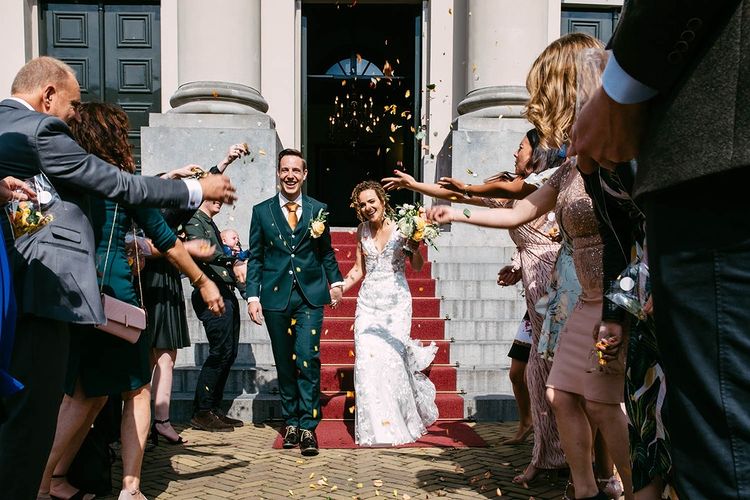A bride and groom leaving a building while confetti is thrown at them, captured by a talented wedding photographer and shared on Instagram.