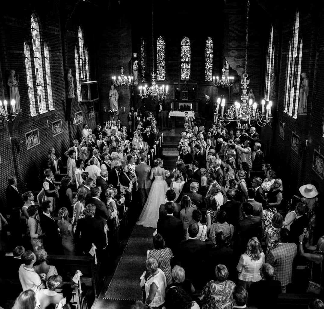 Een zwart-witfoto van een huwelijksceremonie in een kerk.
