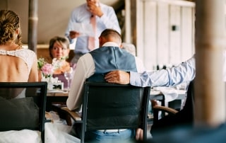 Trouwfoto's van een bruid en bruidegom die aan tafel zitten op hun bruiloft.