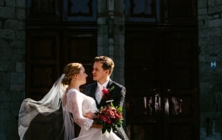 Een bruid en bruidegom dansen hartstochtelijk voor een oud gebouw en maken prachtige trouwfoto's.