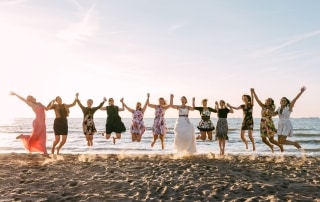 Een groep bruidsmeisjes die tijdens een bruidsdouche in de lucht springen op het strand.