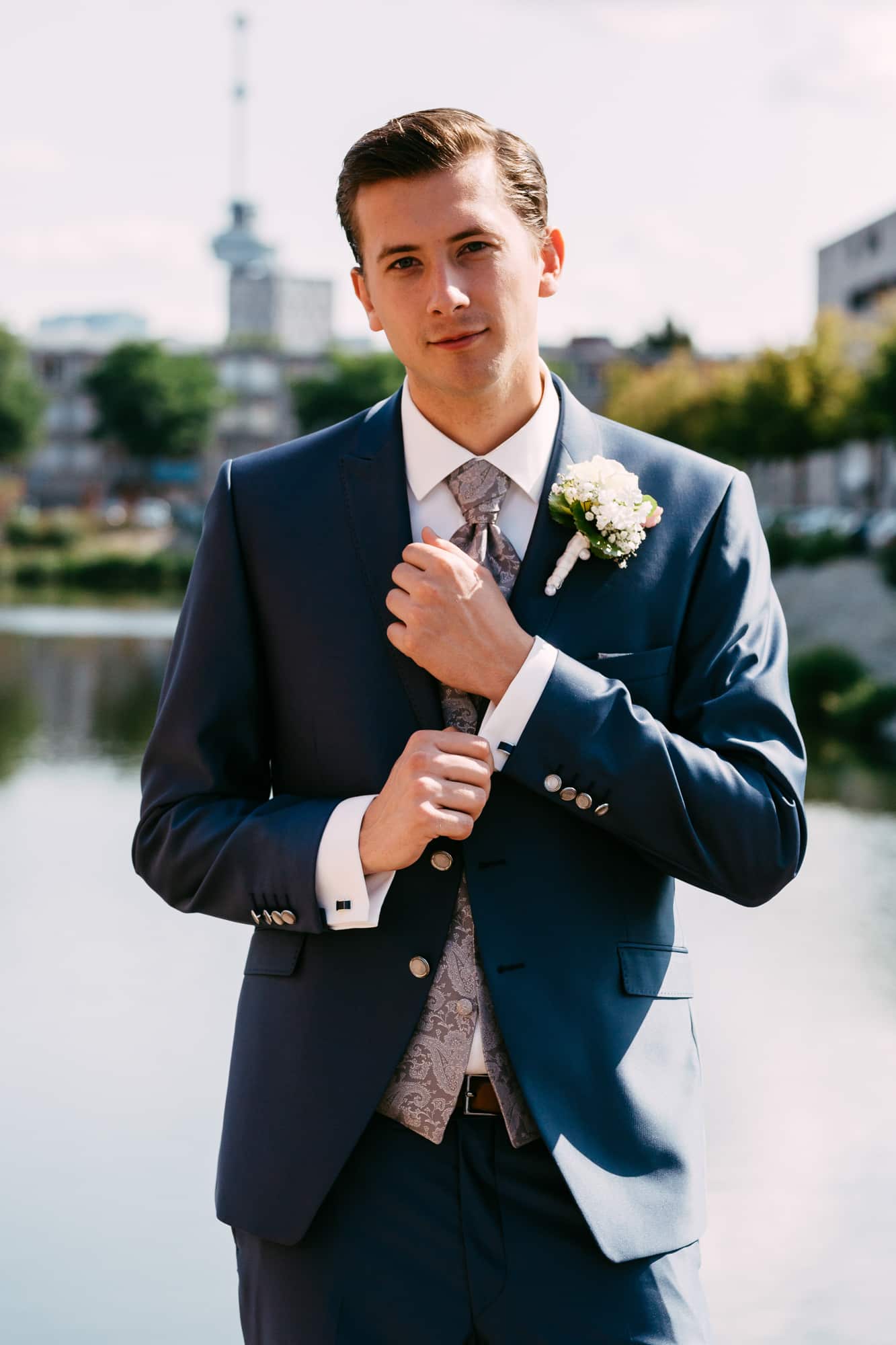 A man in a blue suit poses for a photo at a wedding.