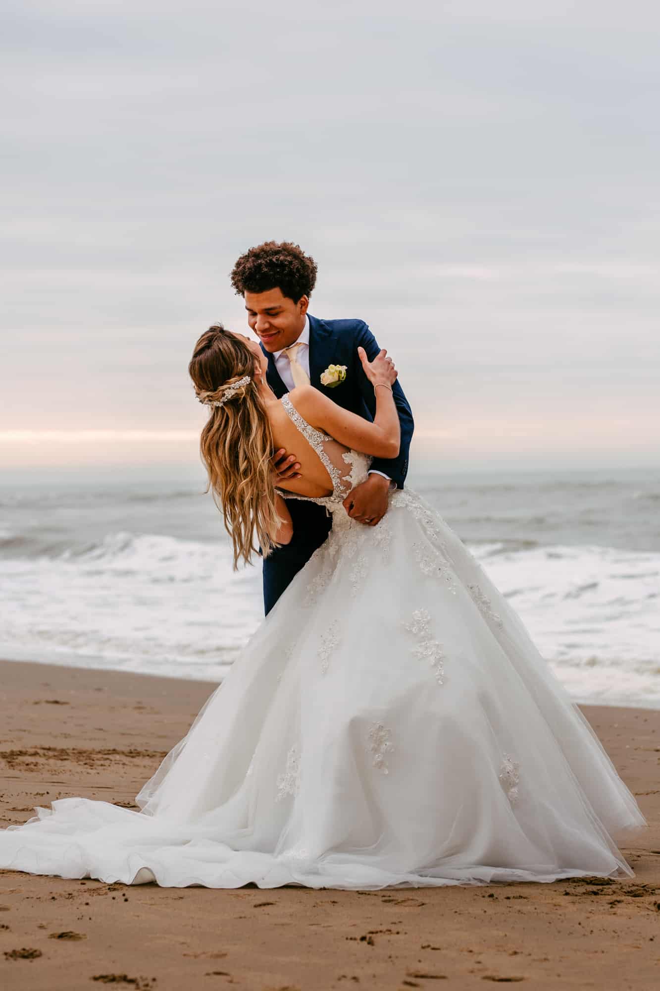 A bride and groom sharing a romantic kiss on the beach, with the bride wearing a beautiful A-line wedding dress.