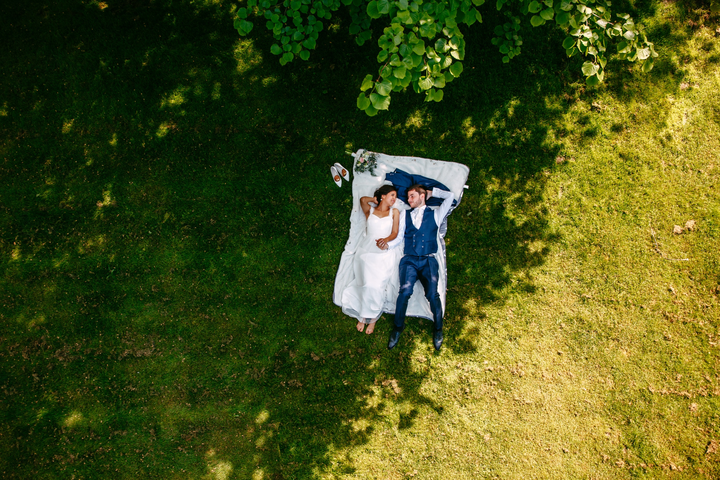 A relaxed bride and groom lying on the grass during their wedding.