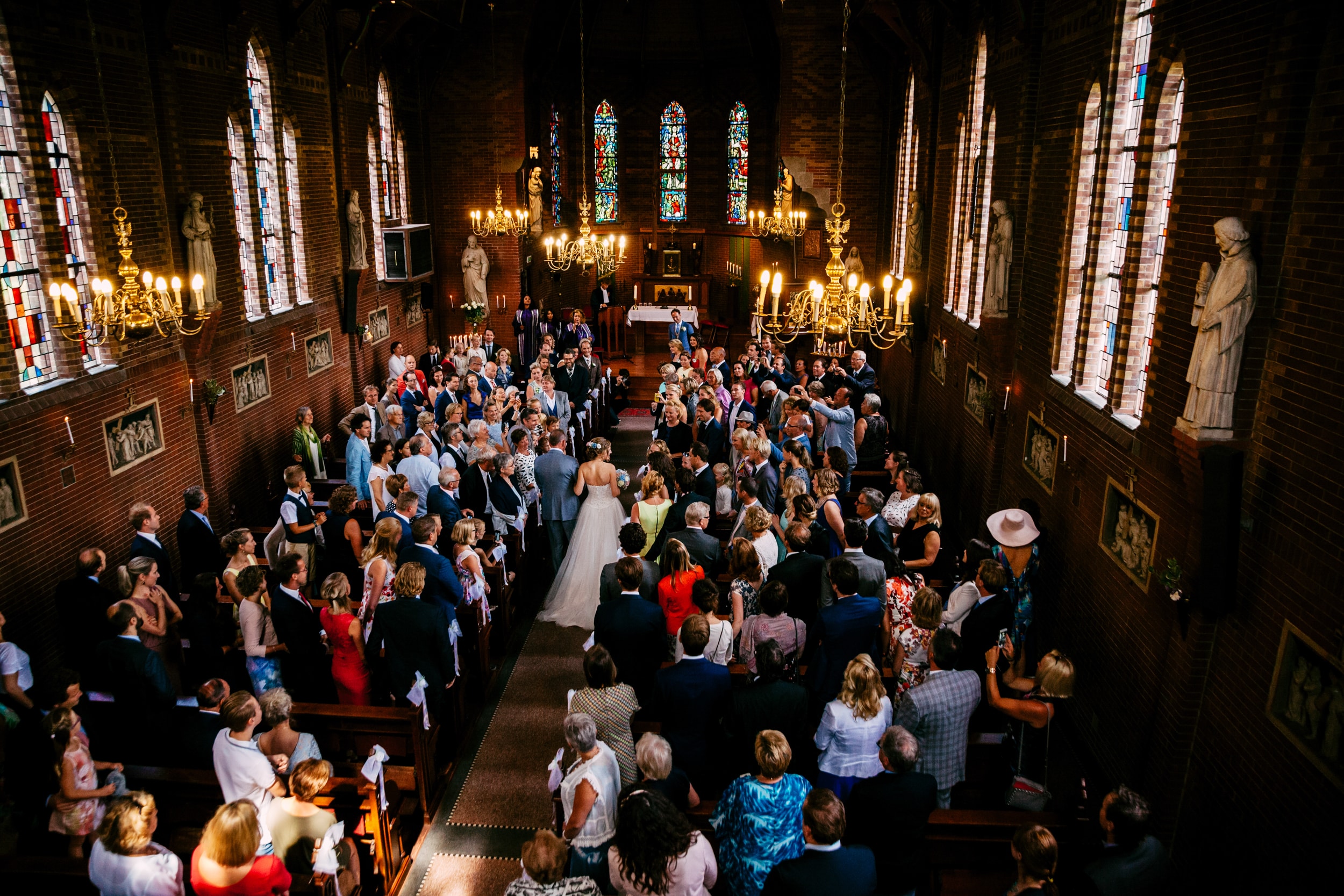Een huwelijksceremonie in een kerk met veel publiek en trouwliedjes.