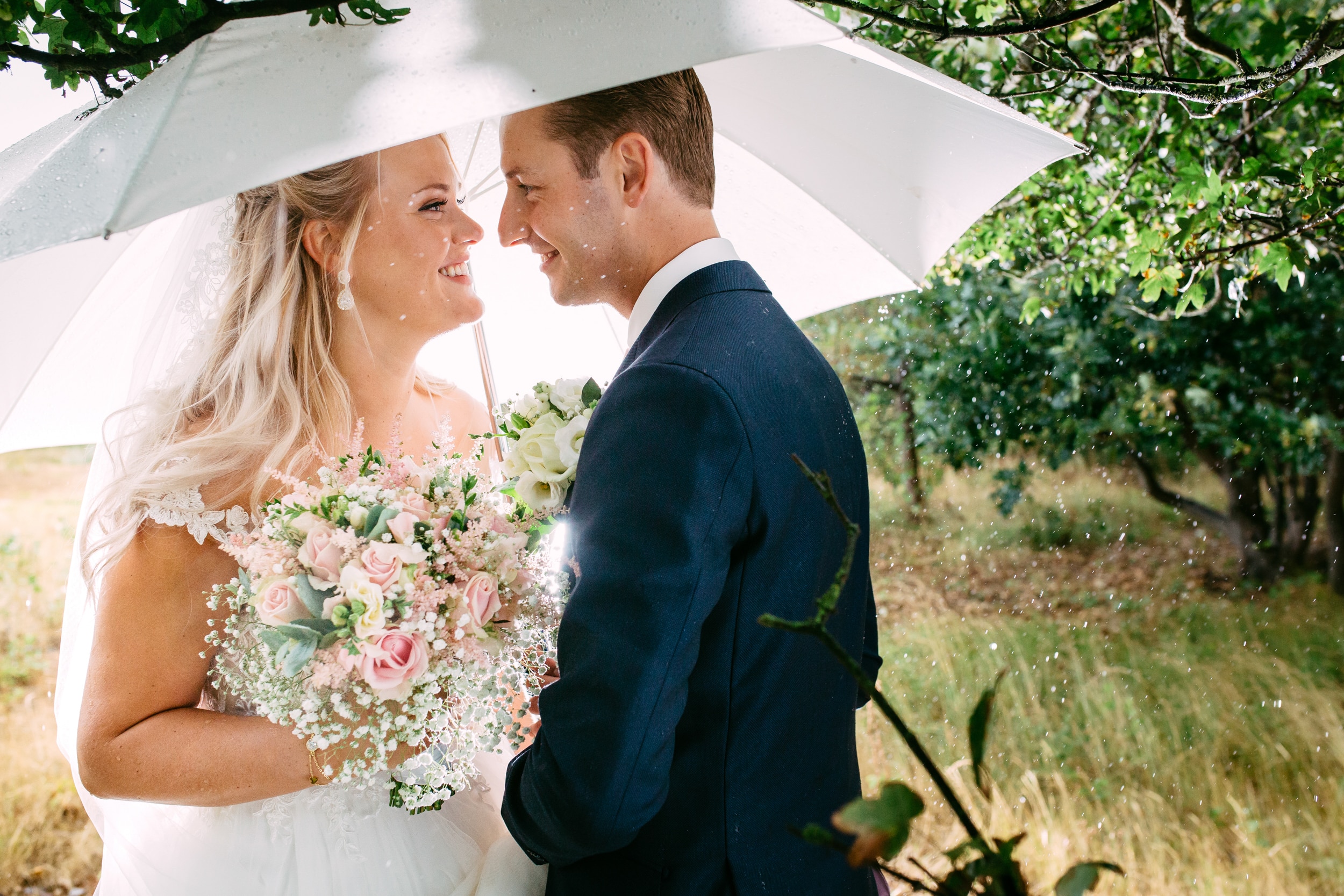 Een Haagse bruid en bruidegom staan onder een paraplu.